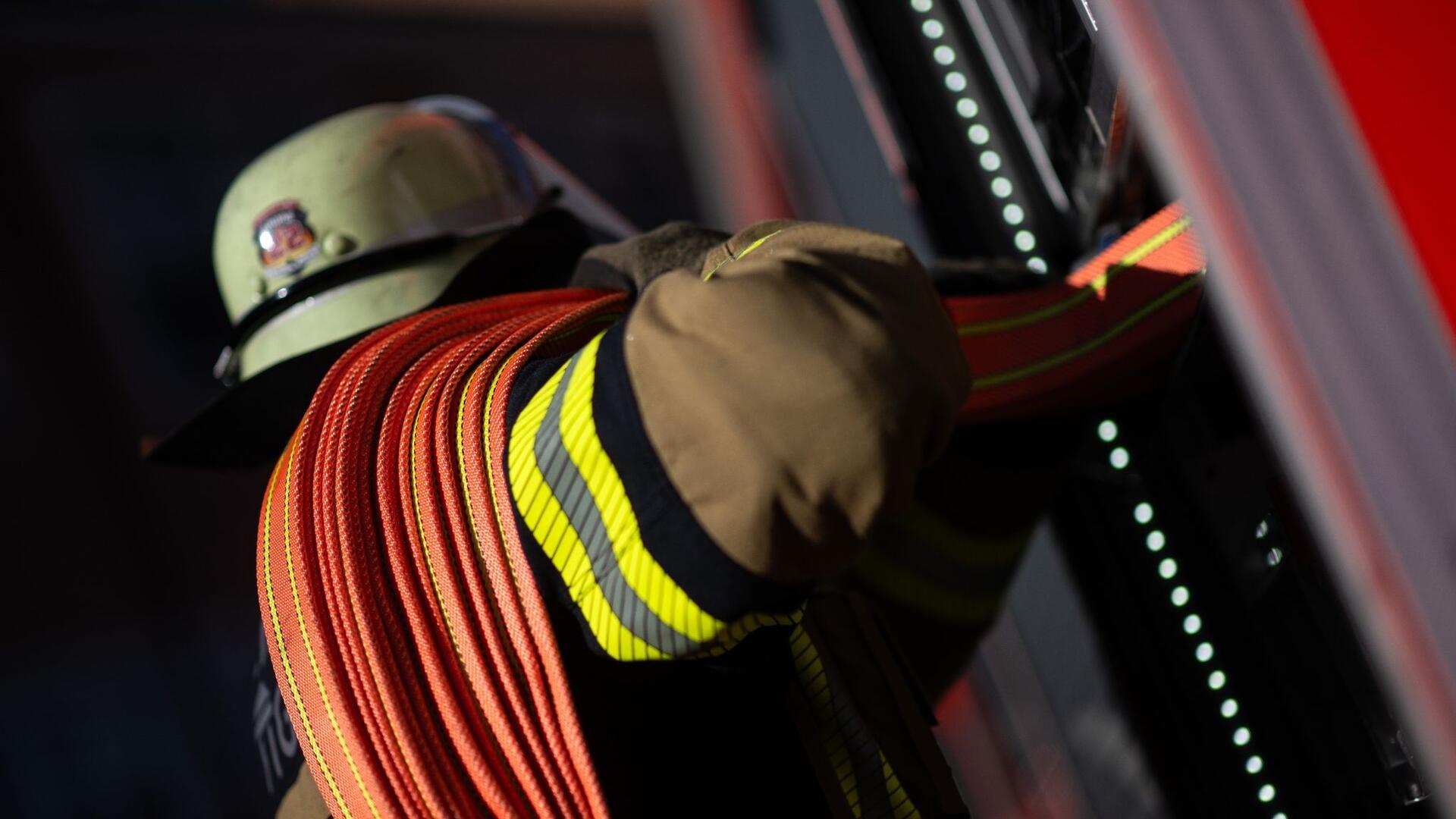 Ein Feuerwehrmann nimmt einen Schlauch aus einem Einsatzfahrzeug.