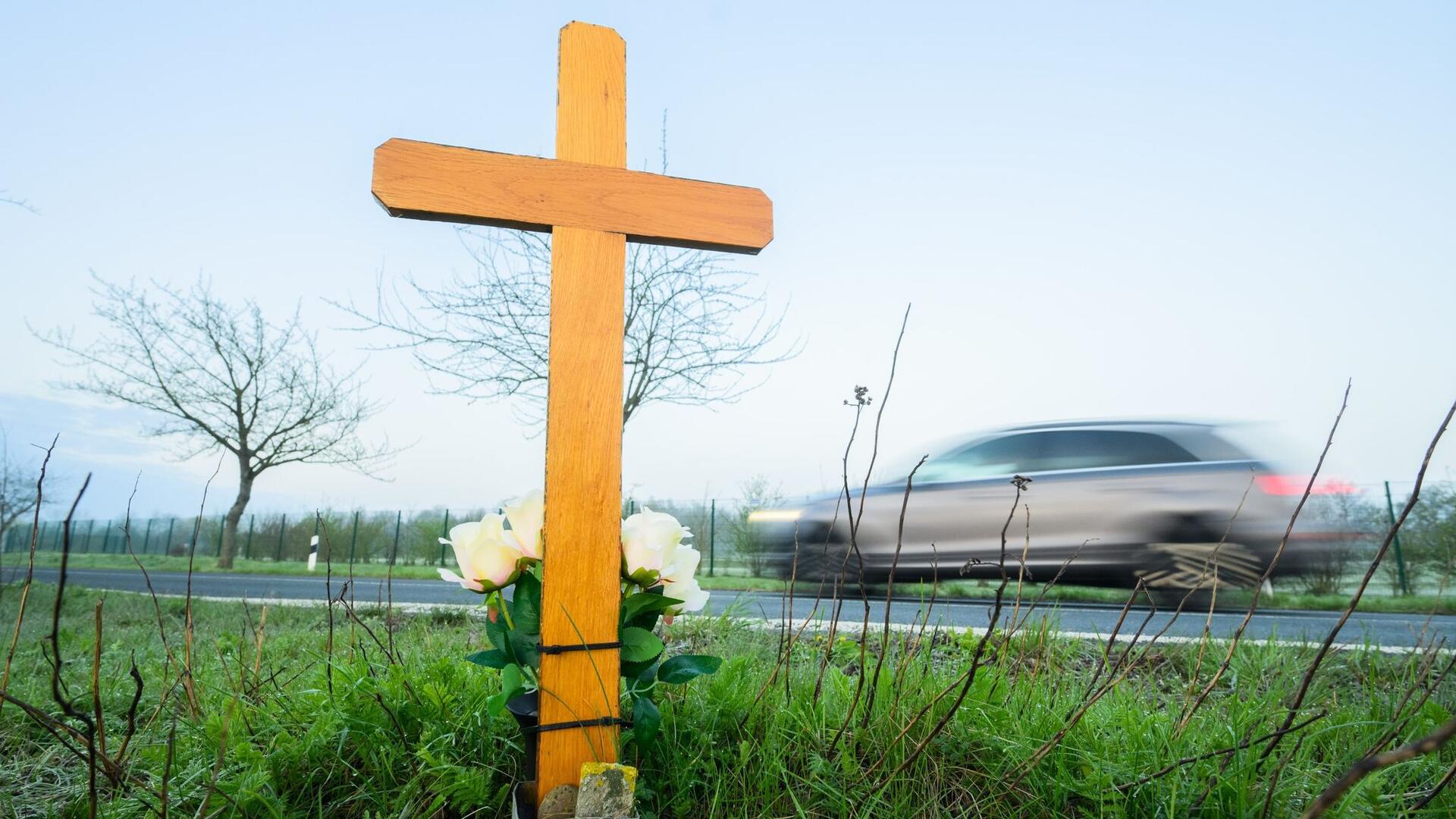 Ein Kreuz zum Gedenken an ein Opfer eines Verkehrsunfalls steht an einer Landstraße.