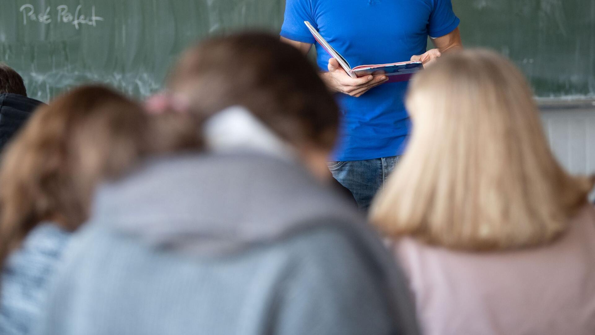 Ein Lehrer steht im Unterricht an der Tafel.