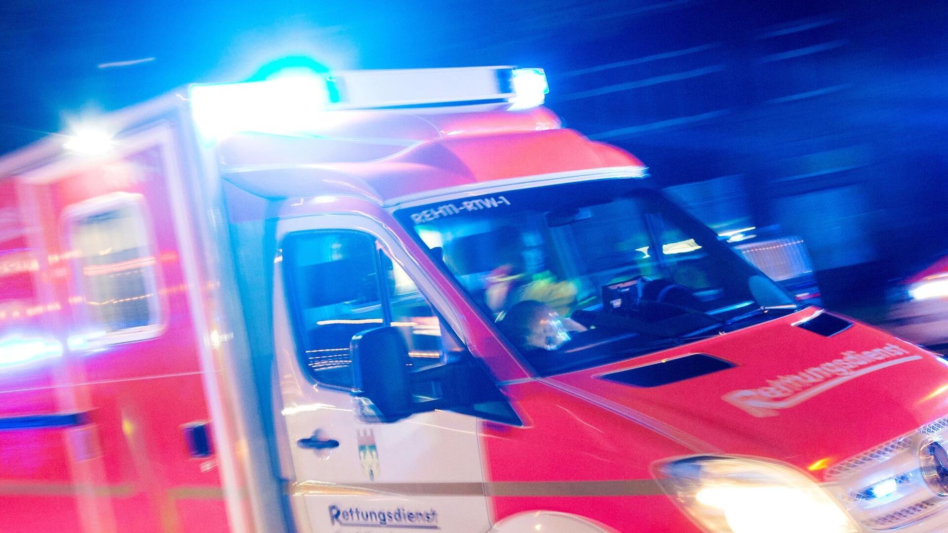 Ein Rettungswagen der Feuerwehr fährt mit Blaulicht durch eine Straße.