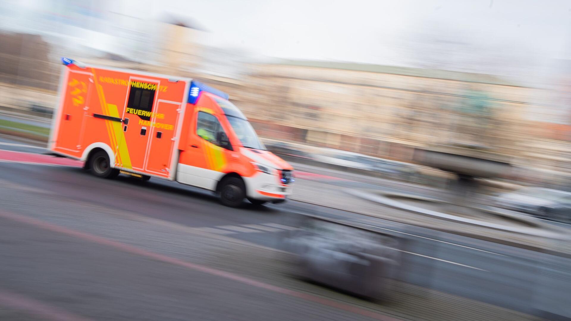 Ein Rettungswagen fährt mit Blaulicht durch eine Innenstadt.