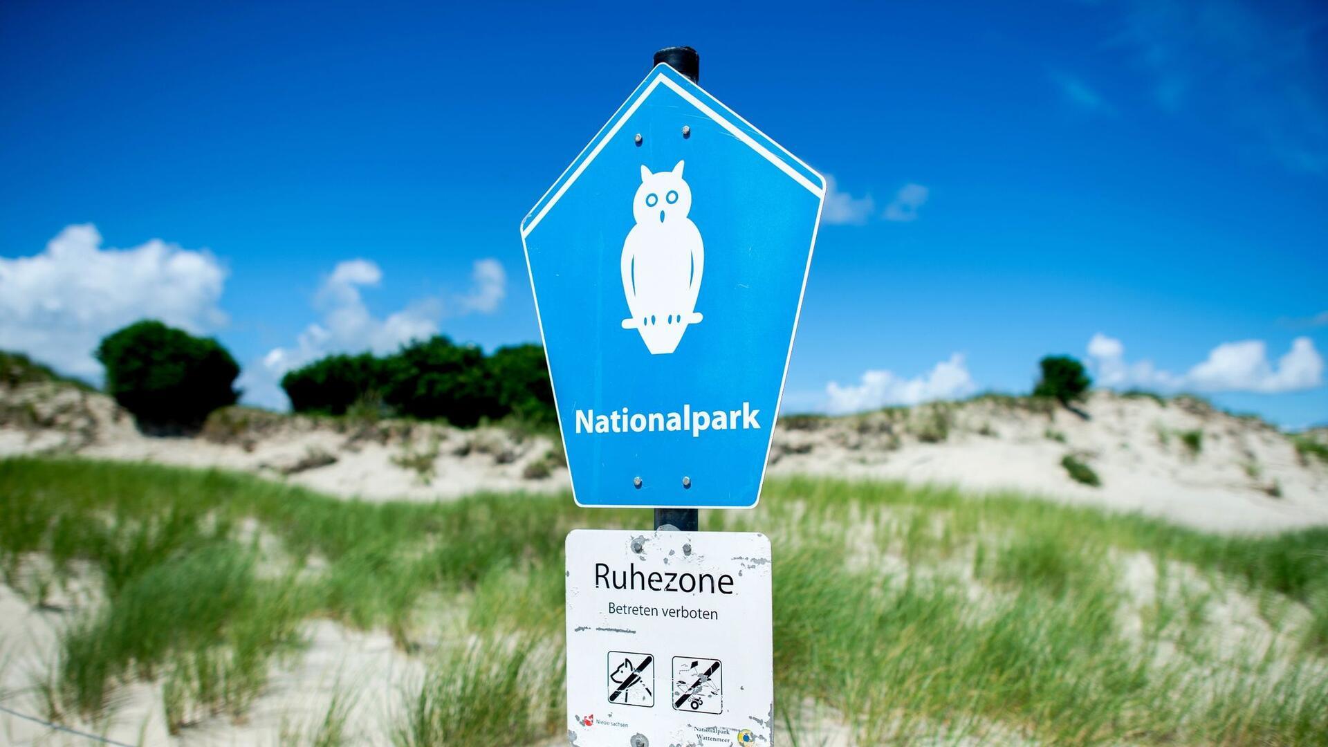 Ein Schild mit der Aufschrift „Nationalpark“ steht vor der Dünenlandschaft am Ostende der Insel Norderney.