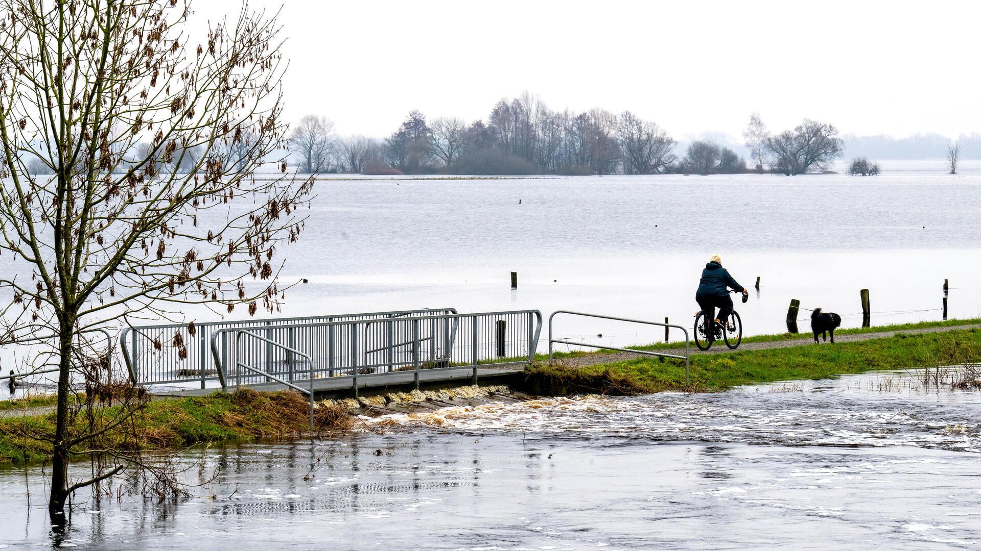 Eine Radfahrerin fährt über den Deich an der Wümme im Bremer Ortsteil Borgfeld. Wegen neuer Regenschauer und nasser Böden führen einige Flüsse in Niedersachsen und Bremen weiterhin viel Wasser. Deshalb gelten Warnungen vor Hochwasser.