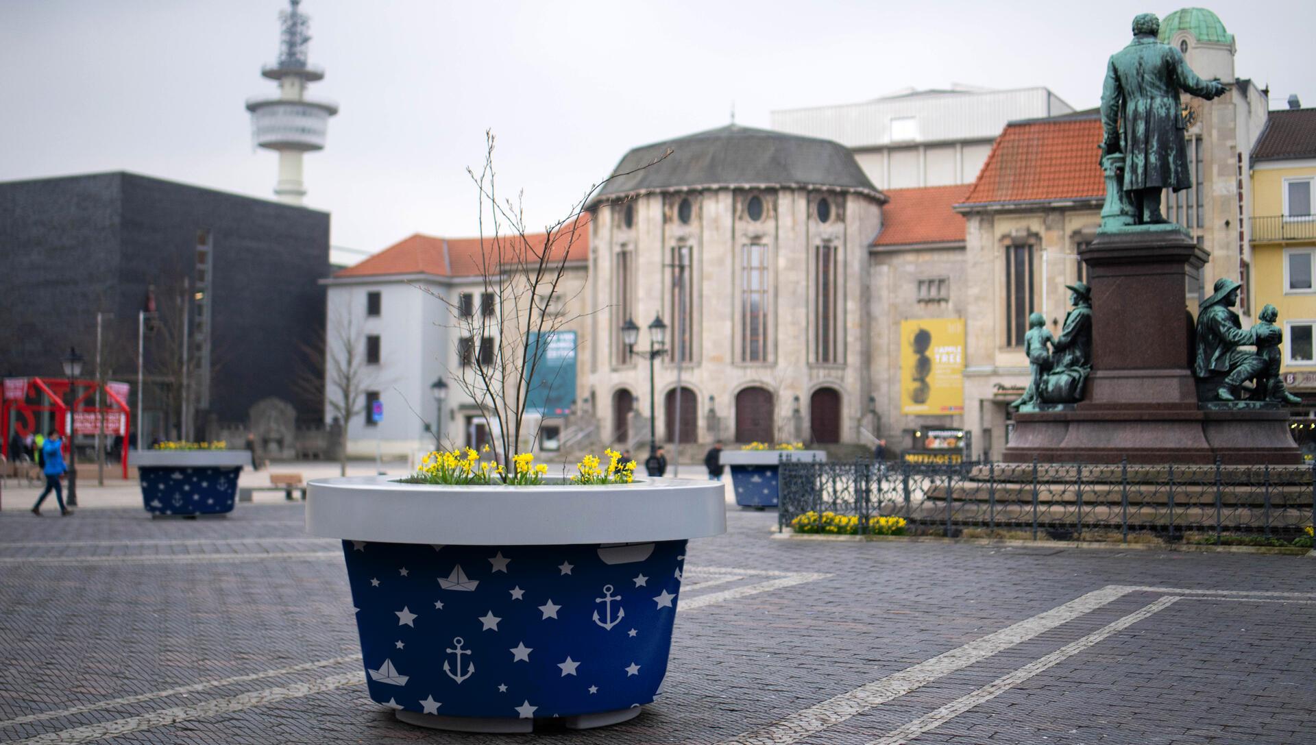 Ein Kübel mit Hafensymbolen darauf ist auf einem öffentlichen Platz zu sehen. 