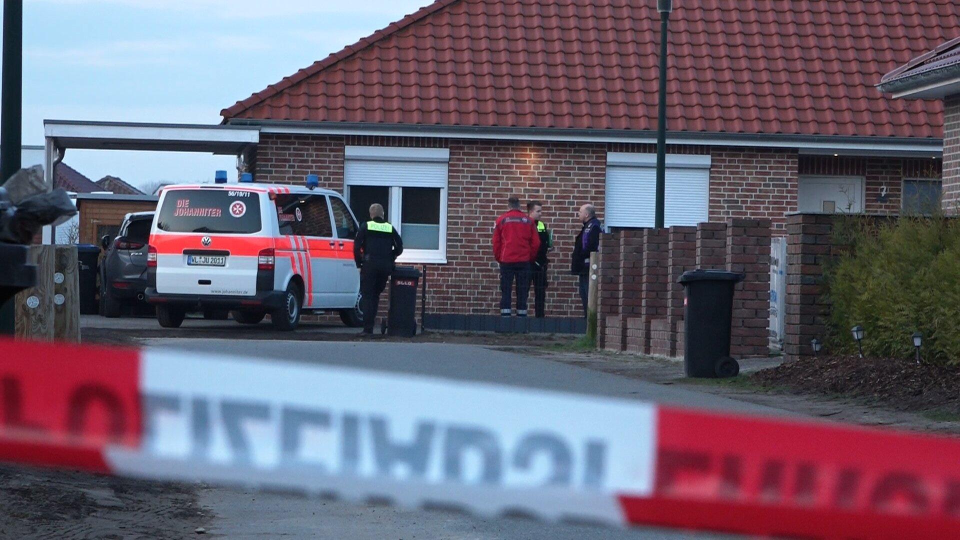 Einsatzkräfte stehen hinter einem Absperrband in Bothel. 