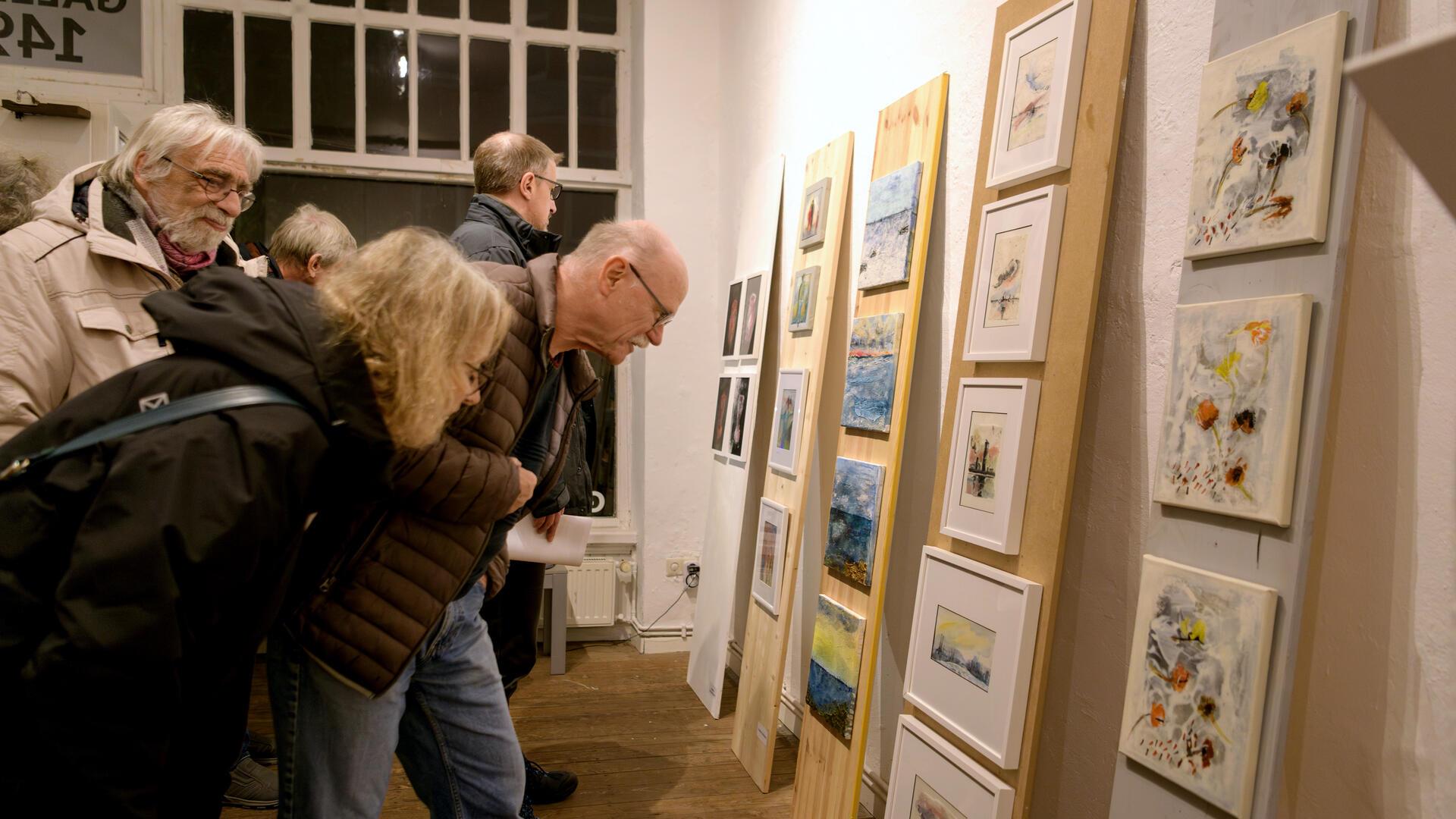 Menschen betrachten Kunstwerke an einer Wand