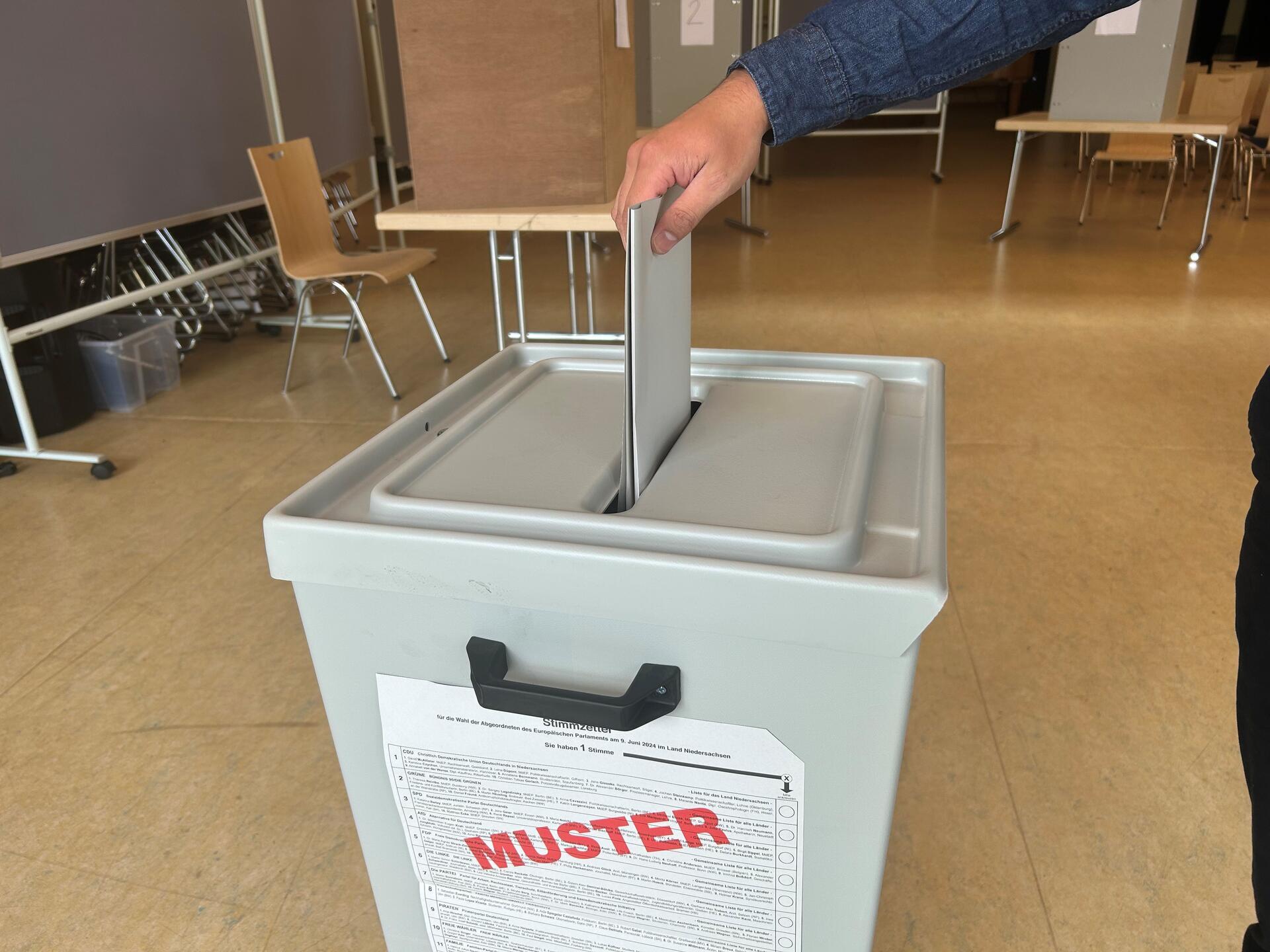 Ein Mann steckt einen Wahlzettel in eine Wahlurne.