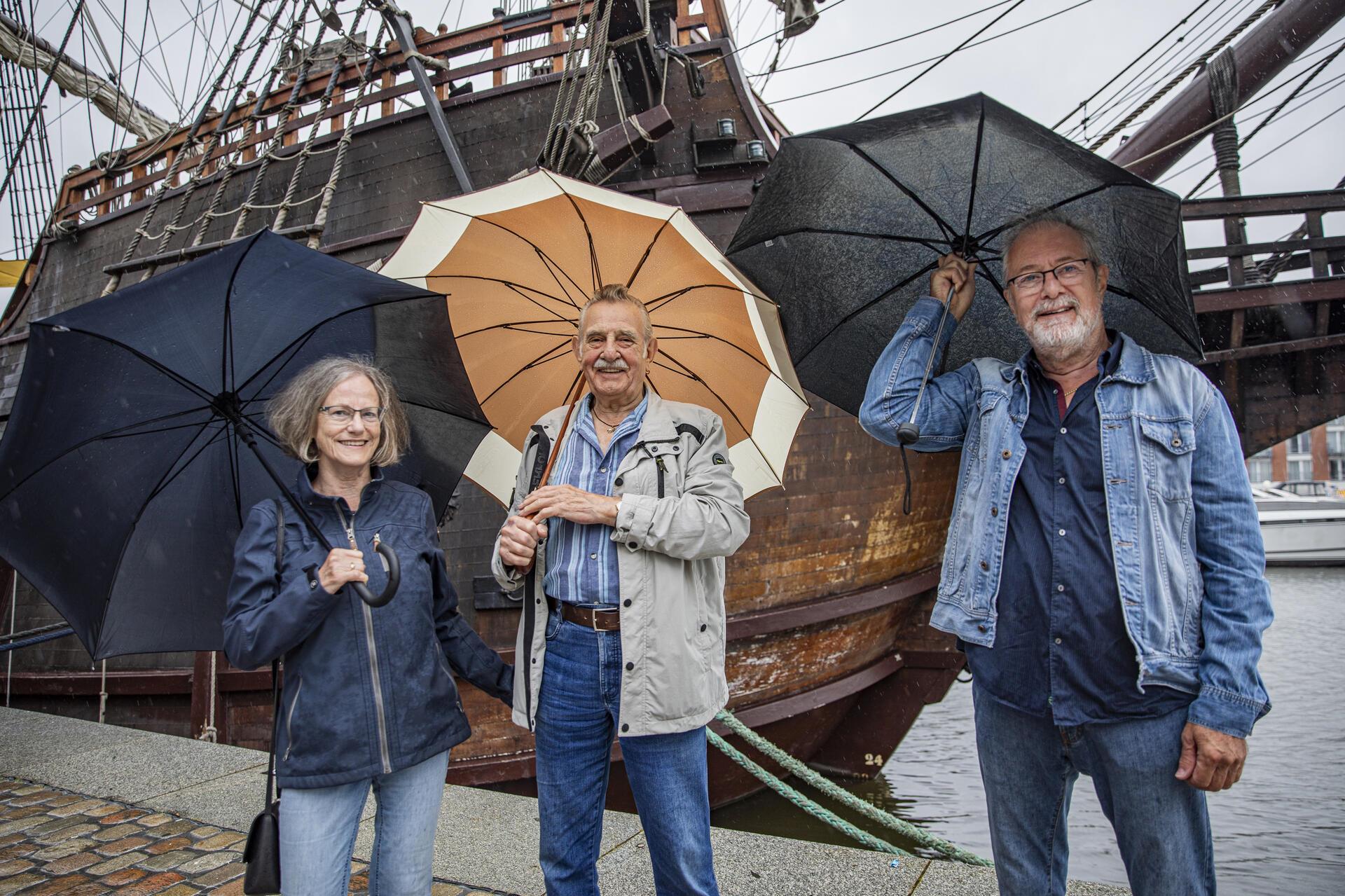 Drei Personen mit Regenschirmen. 