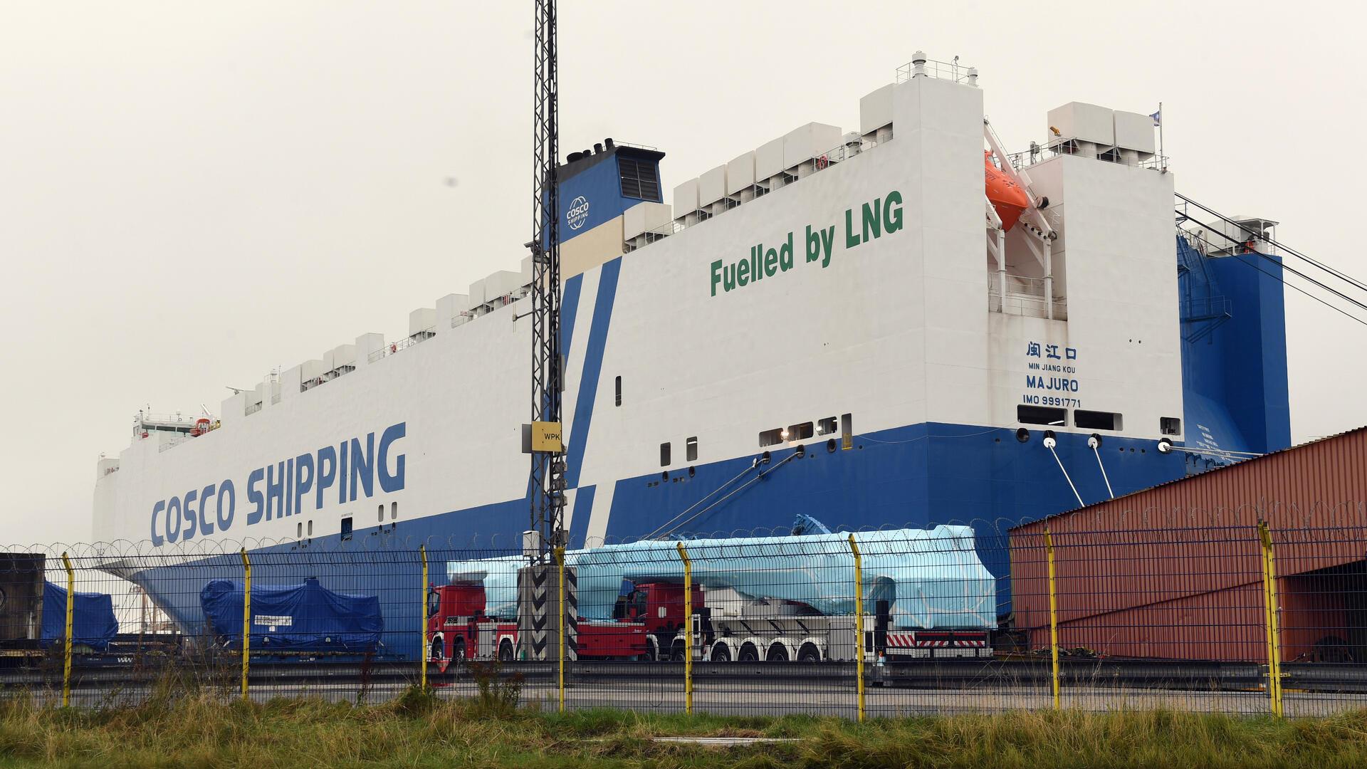 Blau-weißer Autotransporter mit dem Namen der Reederei "Cosco Shipping" und dem Schriftzug "Fuelled by LNG" liegt im Hafen.