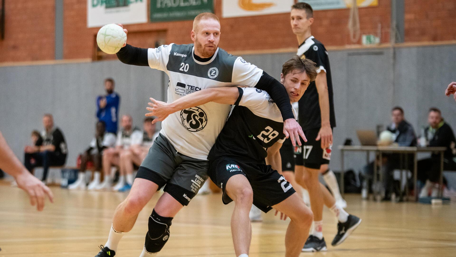 Zwei Männer in schwarz-weißen Trikots kämpfen um einen kleinen Ball.