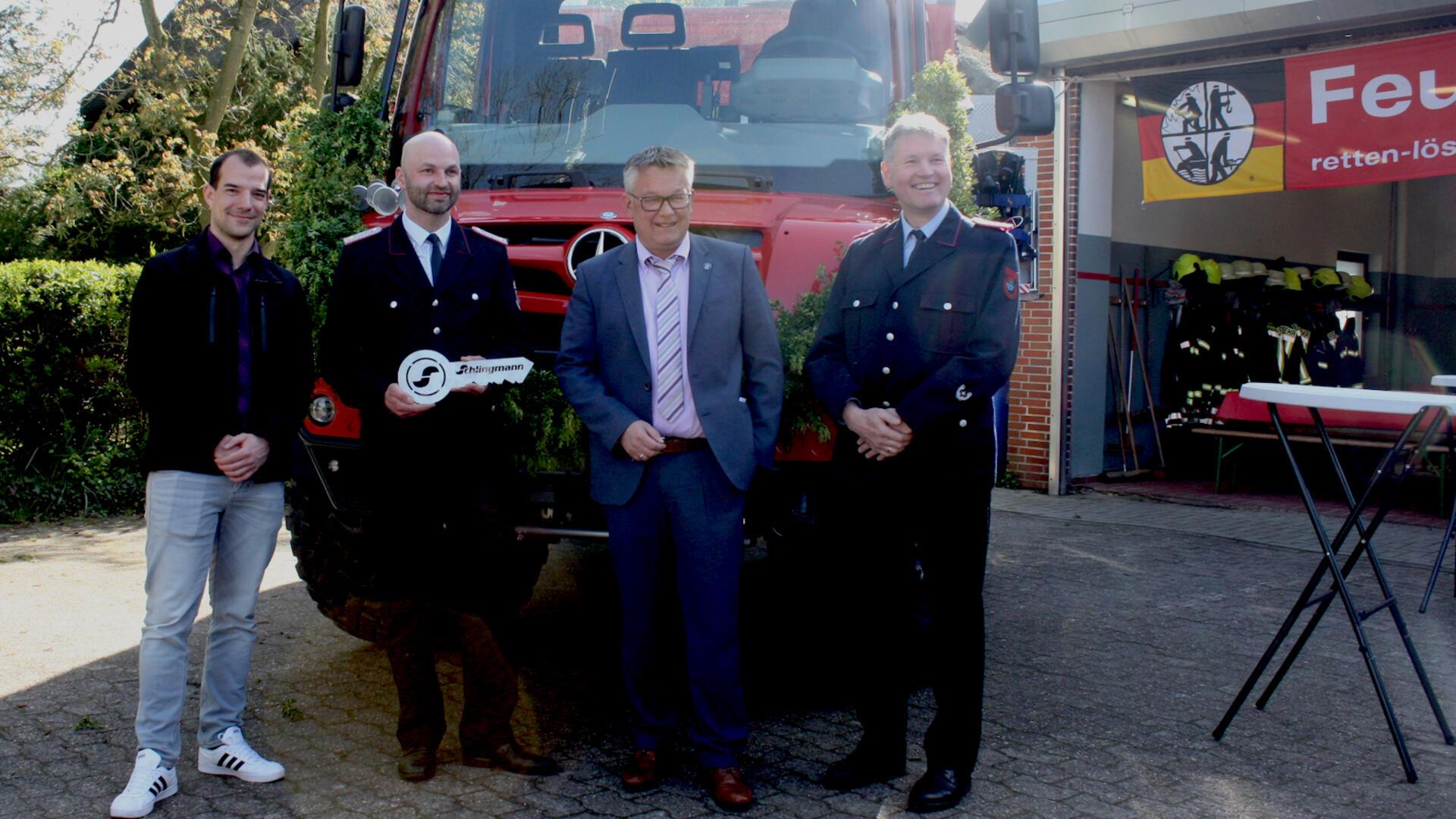 Vier Männer stehen mit einem symbolischen Schlüssel vor einem neuen Löschfahrzeug
