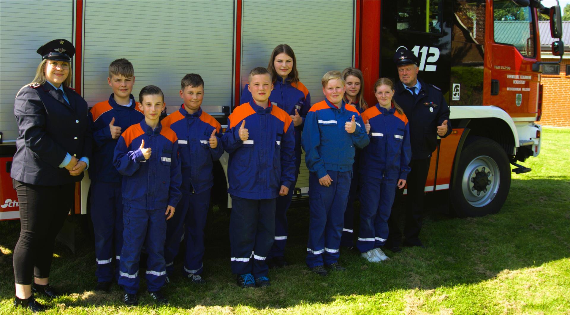 8 Kinder und Jugendliche sowie die zwei Jugendwarte stehen an einem Einsatzfahrzeug der Freiwilligen Feuerwehr Frelsdorf 