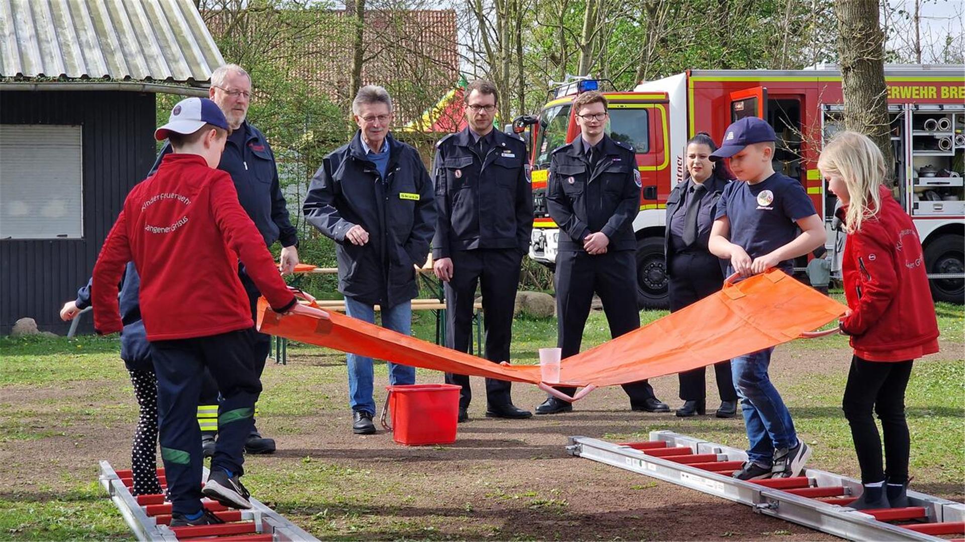 Feuerwehrdezernent Stadtrat Peter Skusa schaut sich zusammen mit dem Jugendfeuerwehrwart Jan Haucke und den Organisatoren Nathalie Zander und Thies Renken gespannt eine Station der Kinderflamme an.