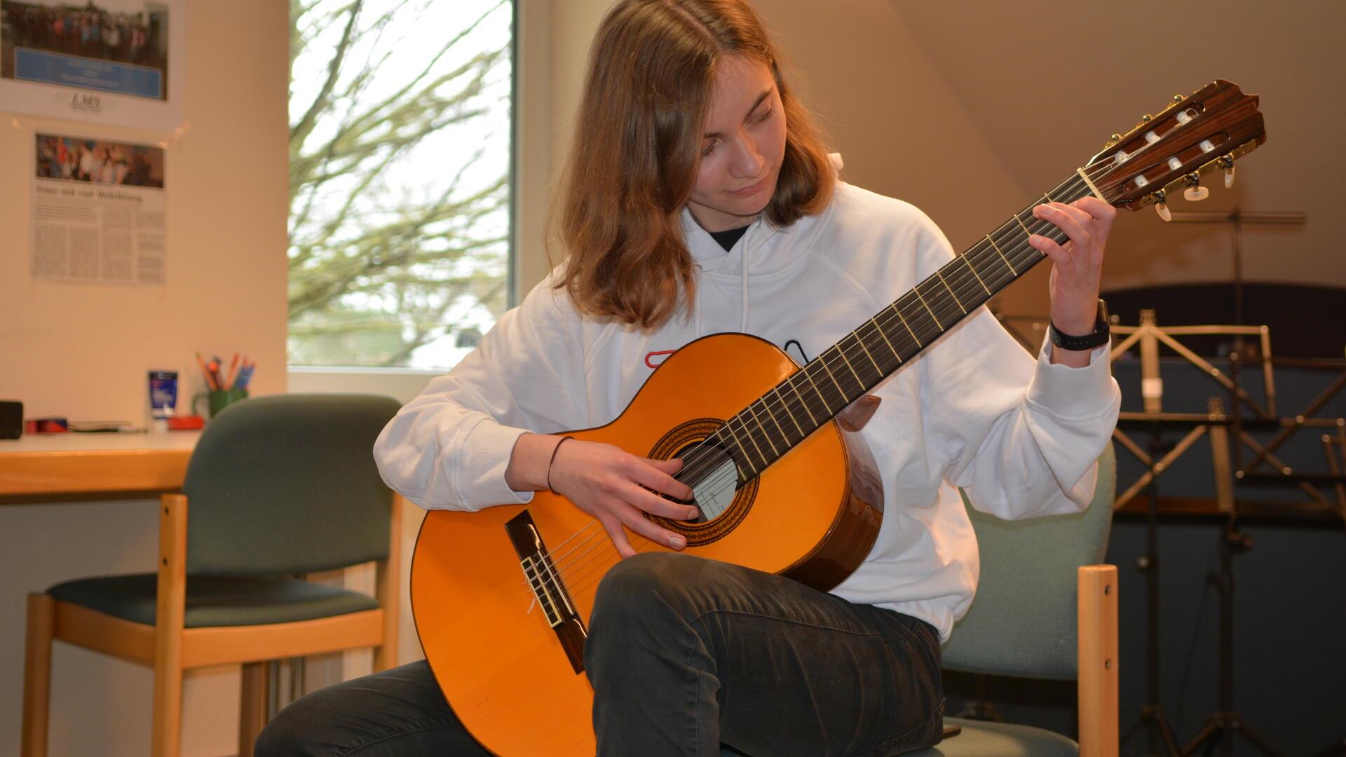 Ein Mädchen mit Gitarre in der Hand.