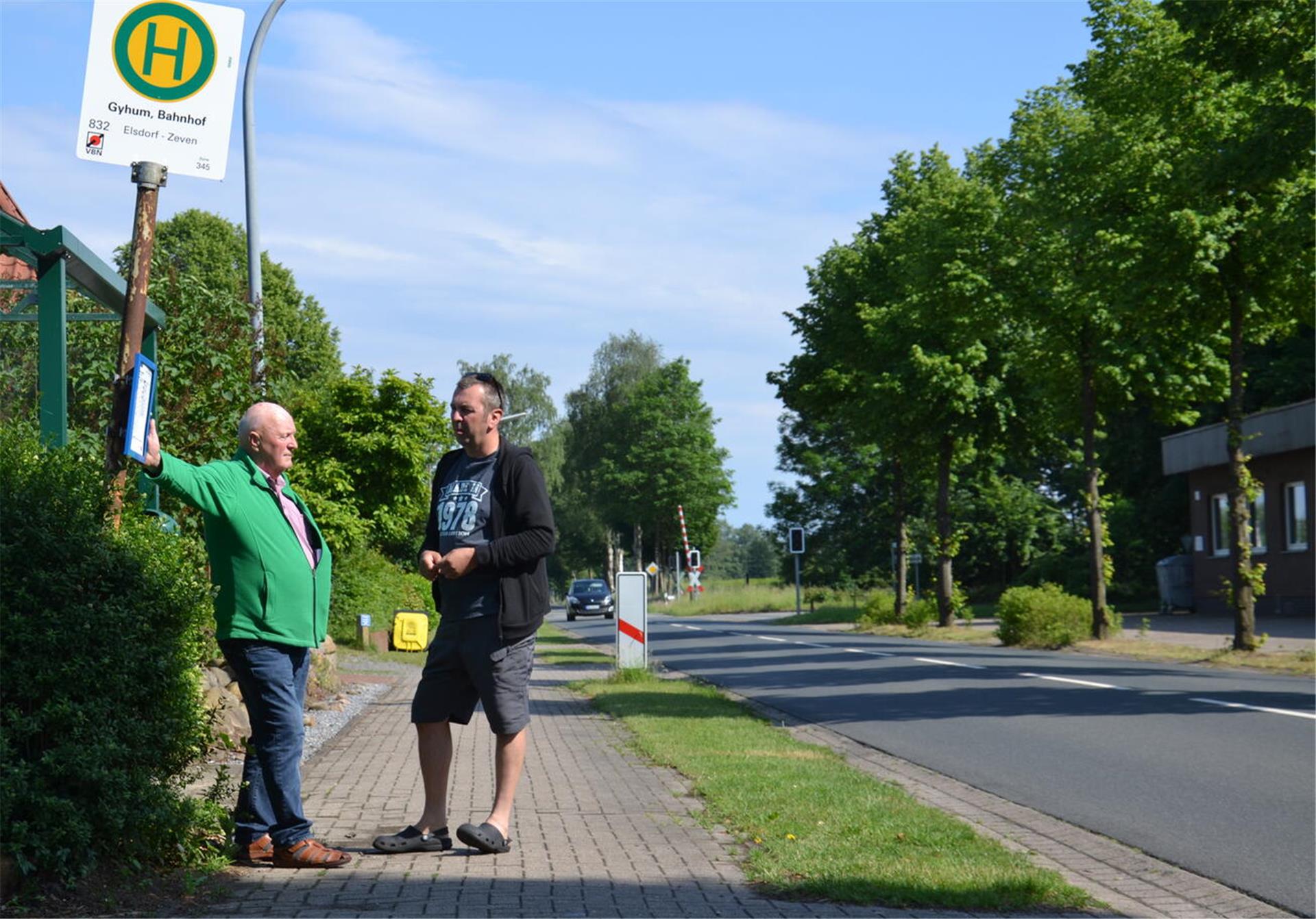 Friedhelm Dreyer und Sven Reichenbach (rechts) stehen an der Bushaltestelle am Bahnhof Gyhum.