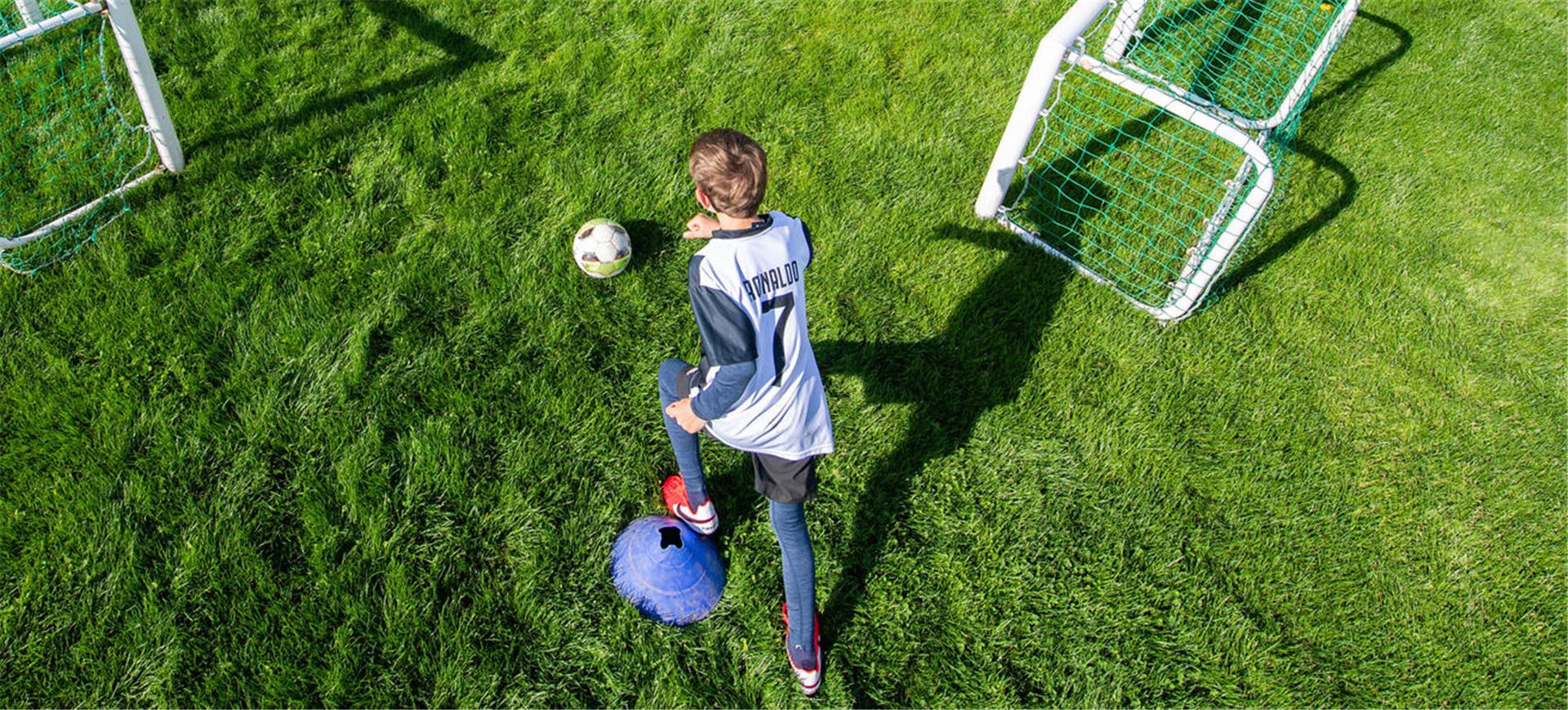 Ein Junge spielt auf dem Rasen Fußball.