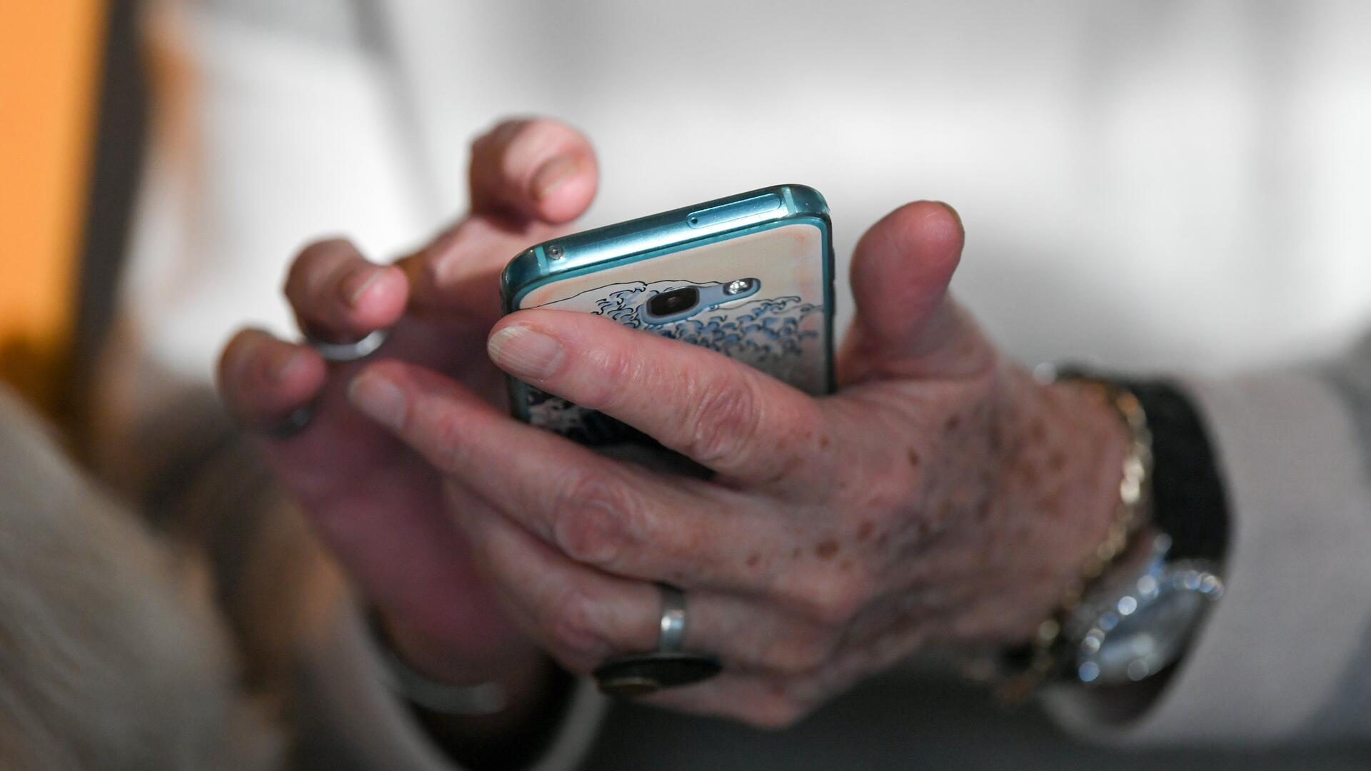 Eine Seniorin hält ihr Smartphone in den Händen.