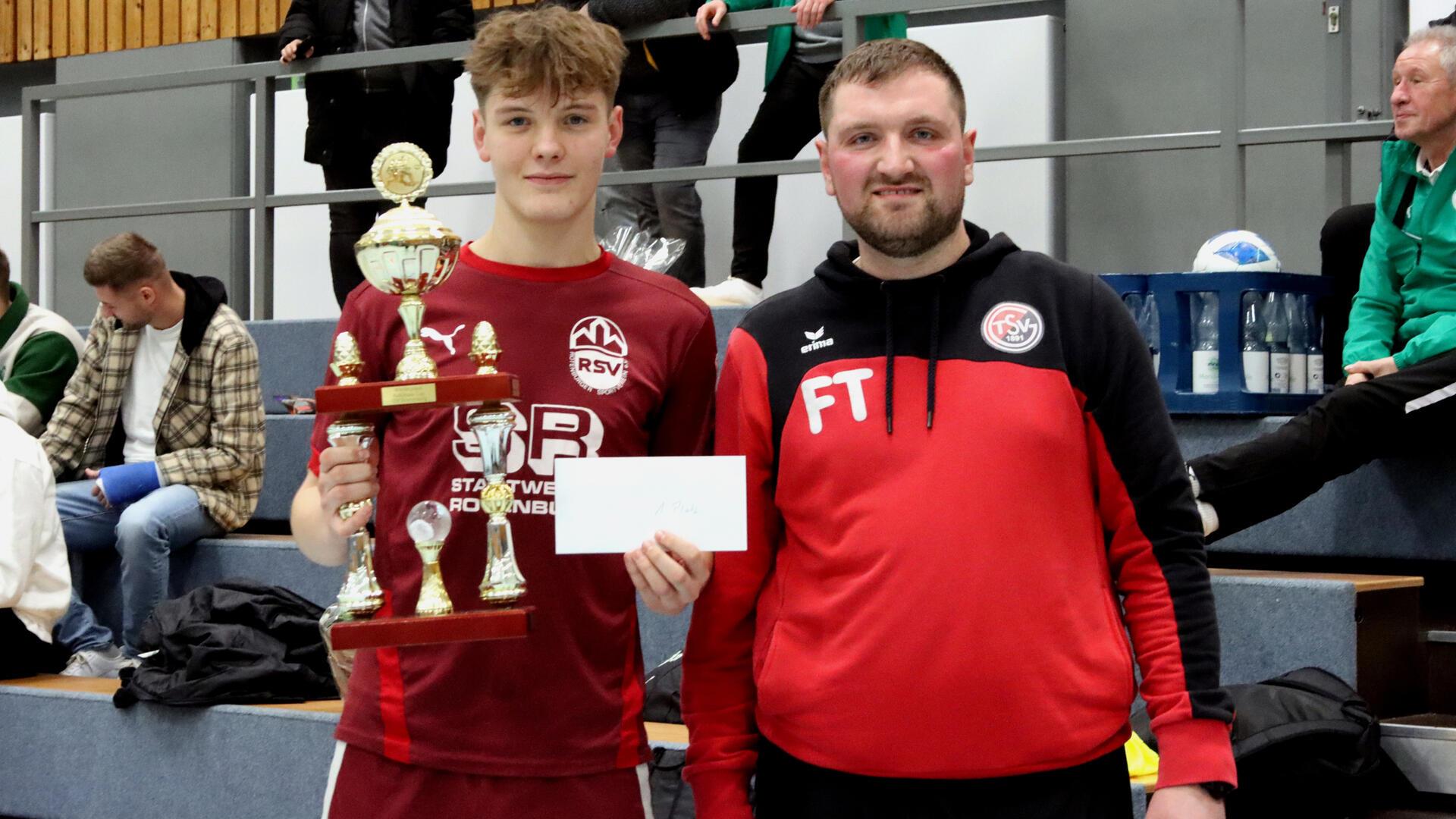 Fußballobmann Fabian Tietjen überreicht dem Rotenburger Kilian Dohna den Pokal und Siegerscheck.