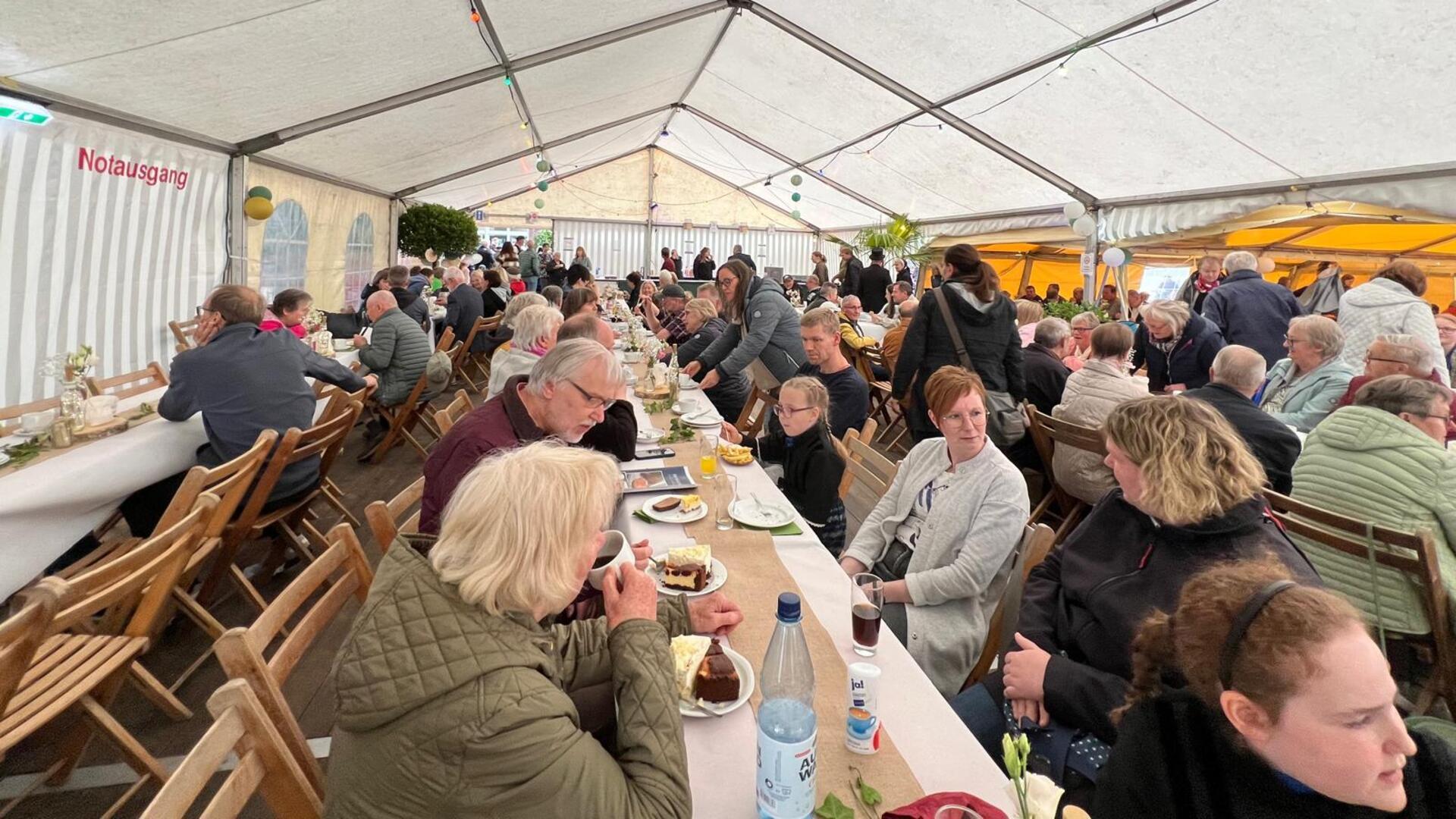 Gäste genießen Kaffee und Kuchen im Festzelt. 