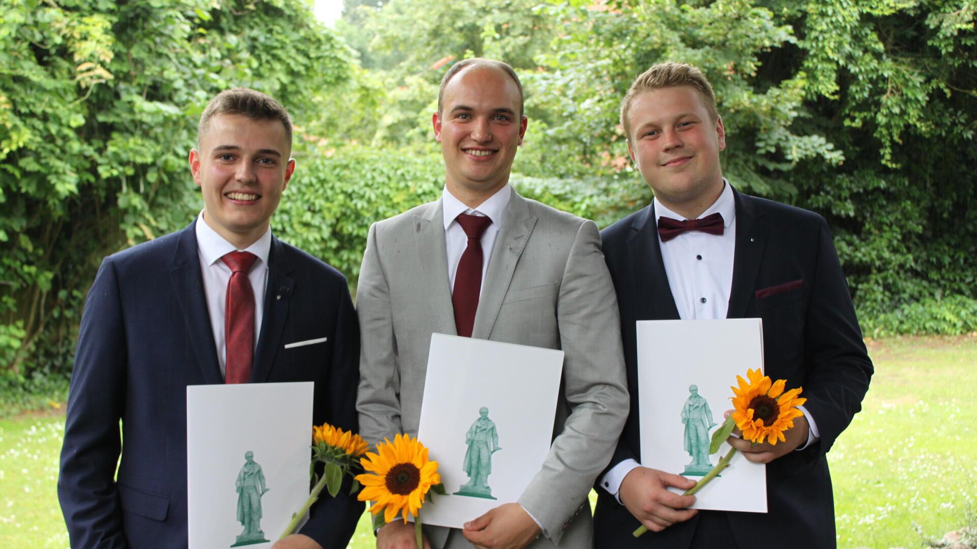 Christoph Meyer aus Bötersen, Clawes Heins aus Rockstedt sowie Fiete Petersen aus Zeven mit Urkunde und Blume in der Hand. 