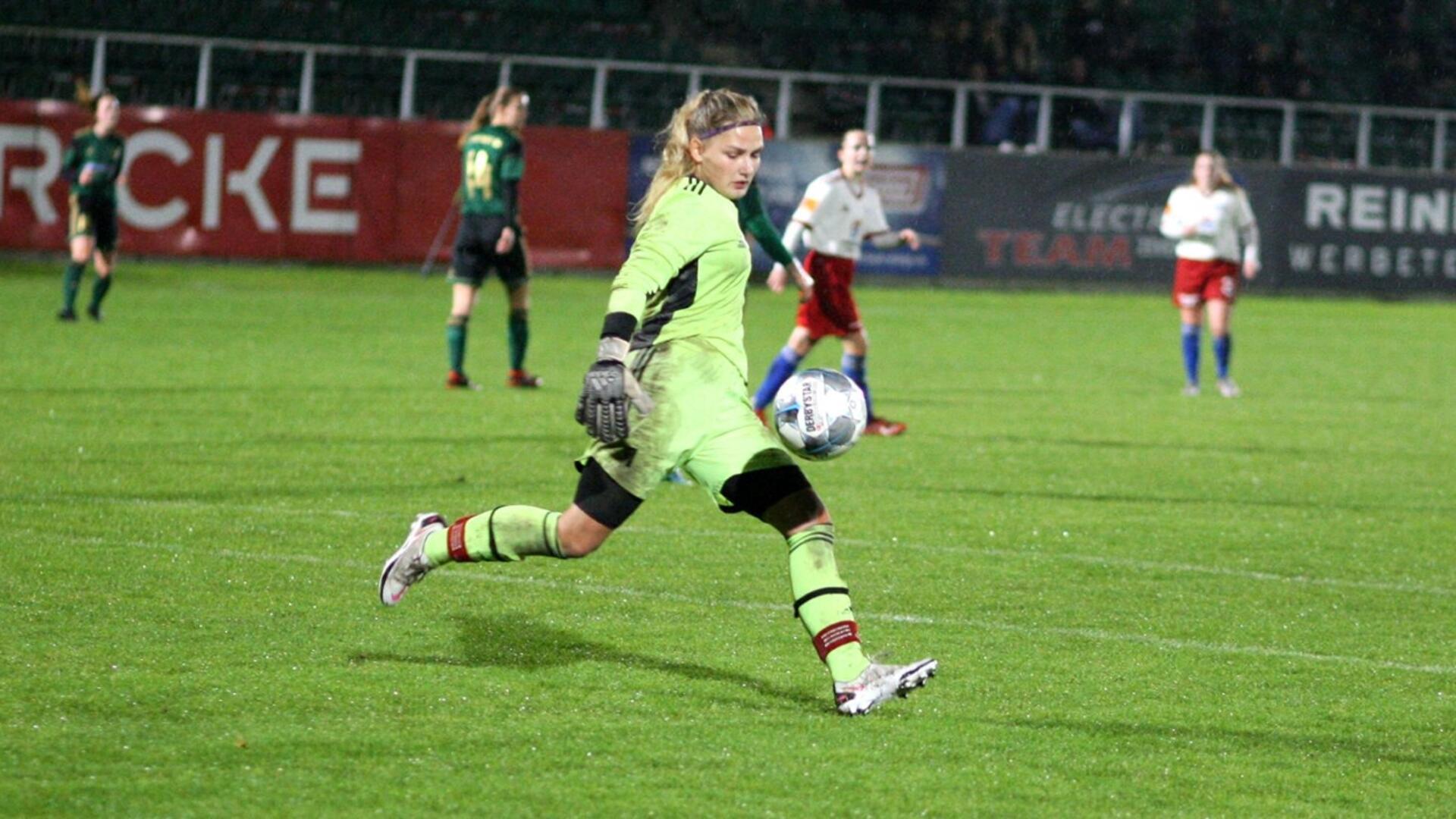 eine Frau im grünen Trikot schießt einen Ball.