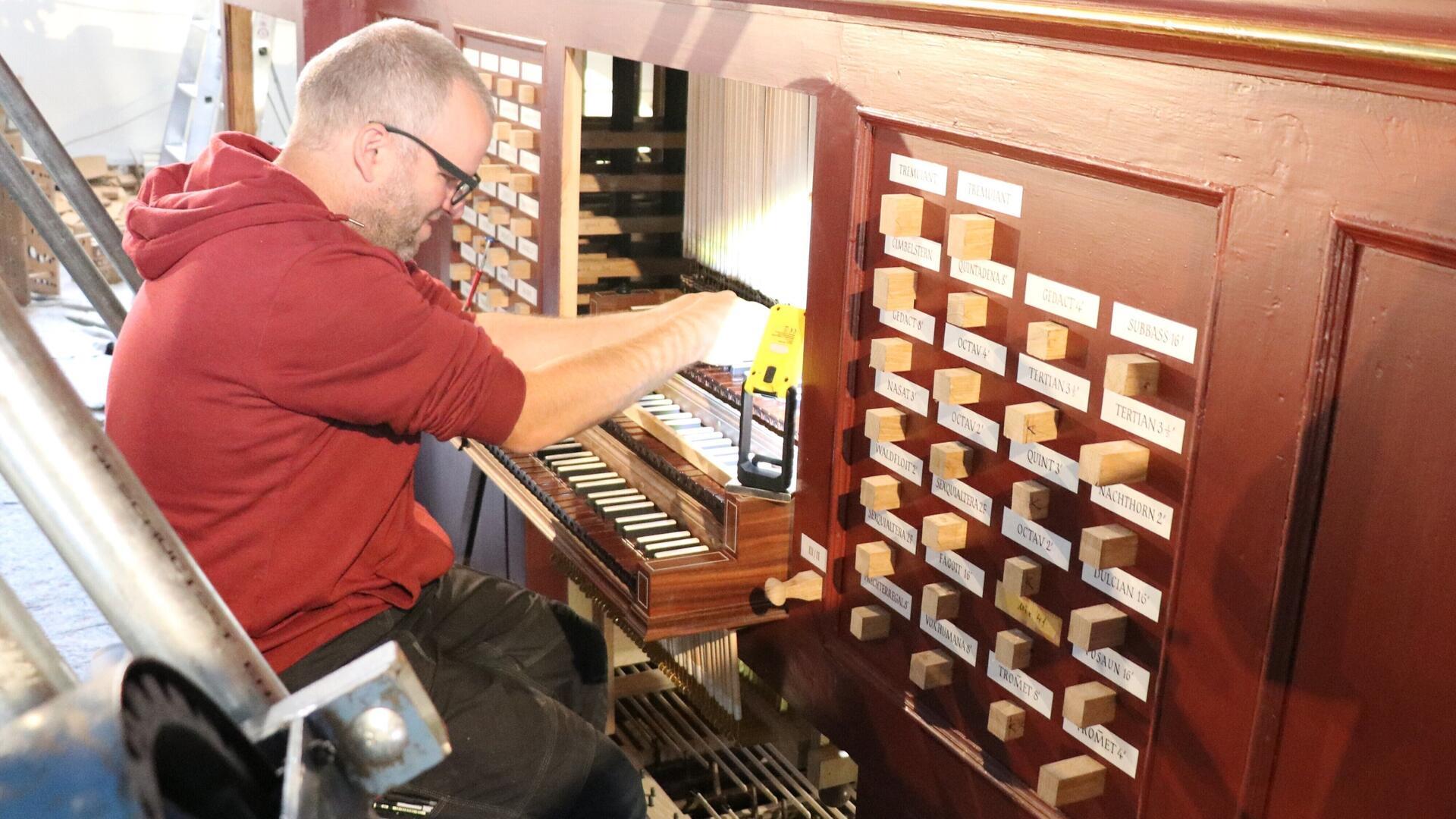 Handwerksmeister Dennis Backer reguliert die Tasten einer Orgel