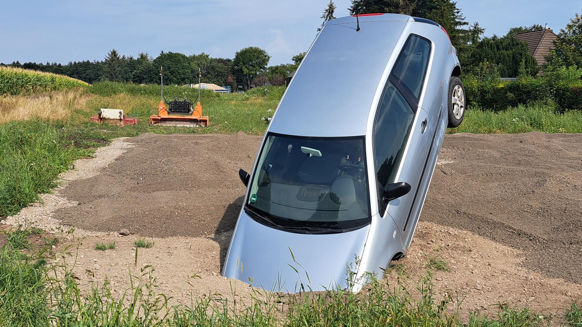 Hat hier jemand schlecht geparkt? In einem Feld bei Bramstedt steckt ein Auto im Boden. 
