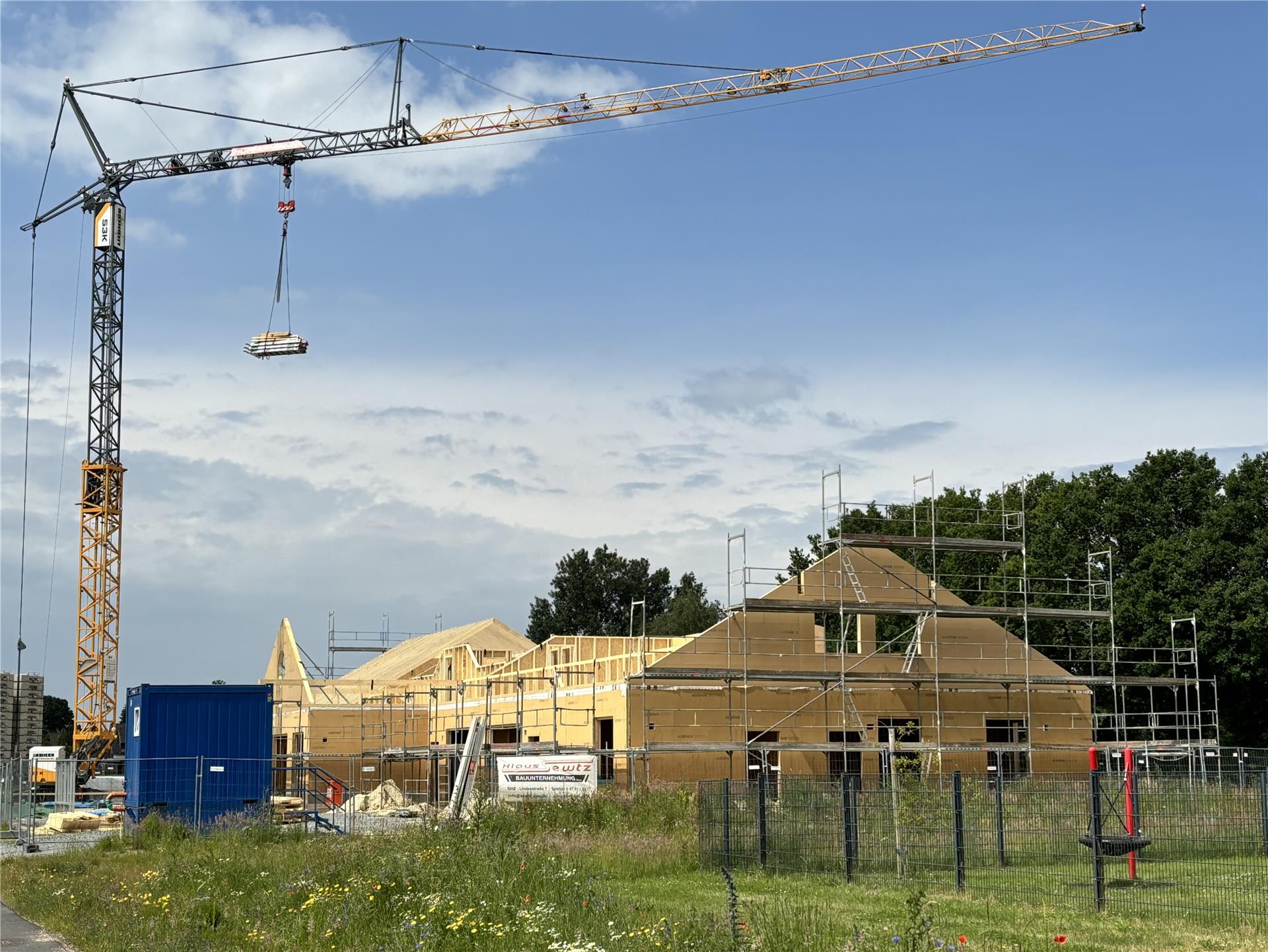 Ein Kran thront über der Baustelle eines Gebäudes in Holzbauweise.