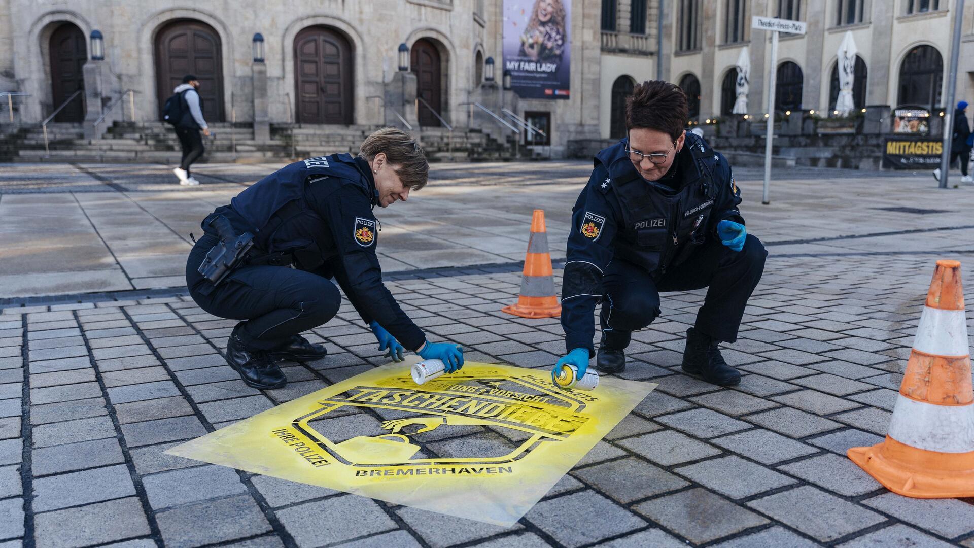 Im Rahmen einer Präventionsaktion auf dem Bremerhavener Weihnachtsmarkt sprühten Polizeibeamtinnen Warnhinweise in der Innenstadt. Taschendieben soll es möglichst schwer gemacht werden. 