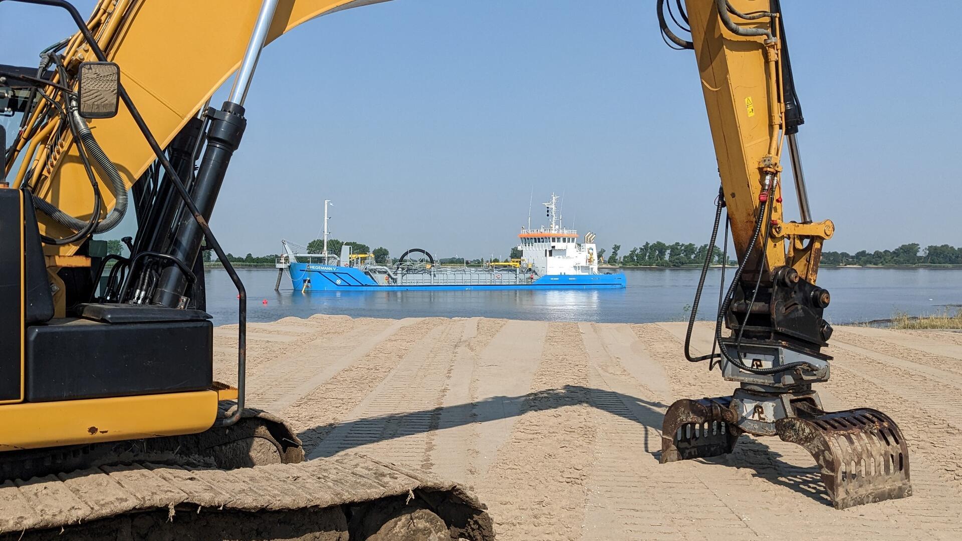 Hydraulikbagger auf einer Sandfläche an der Weser