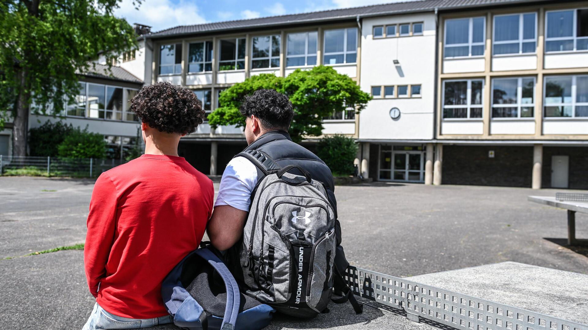 Schüler sitzen auf einer Tischtennisplatte im Schulhof,