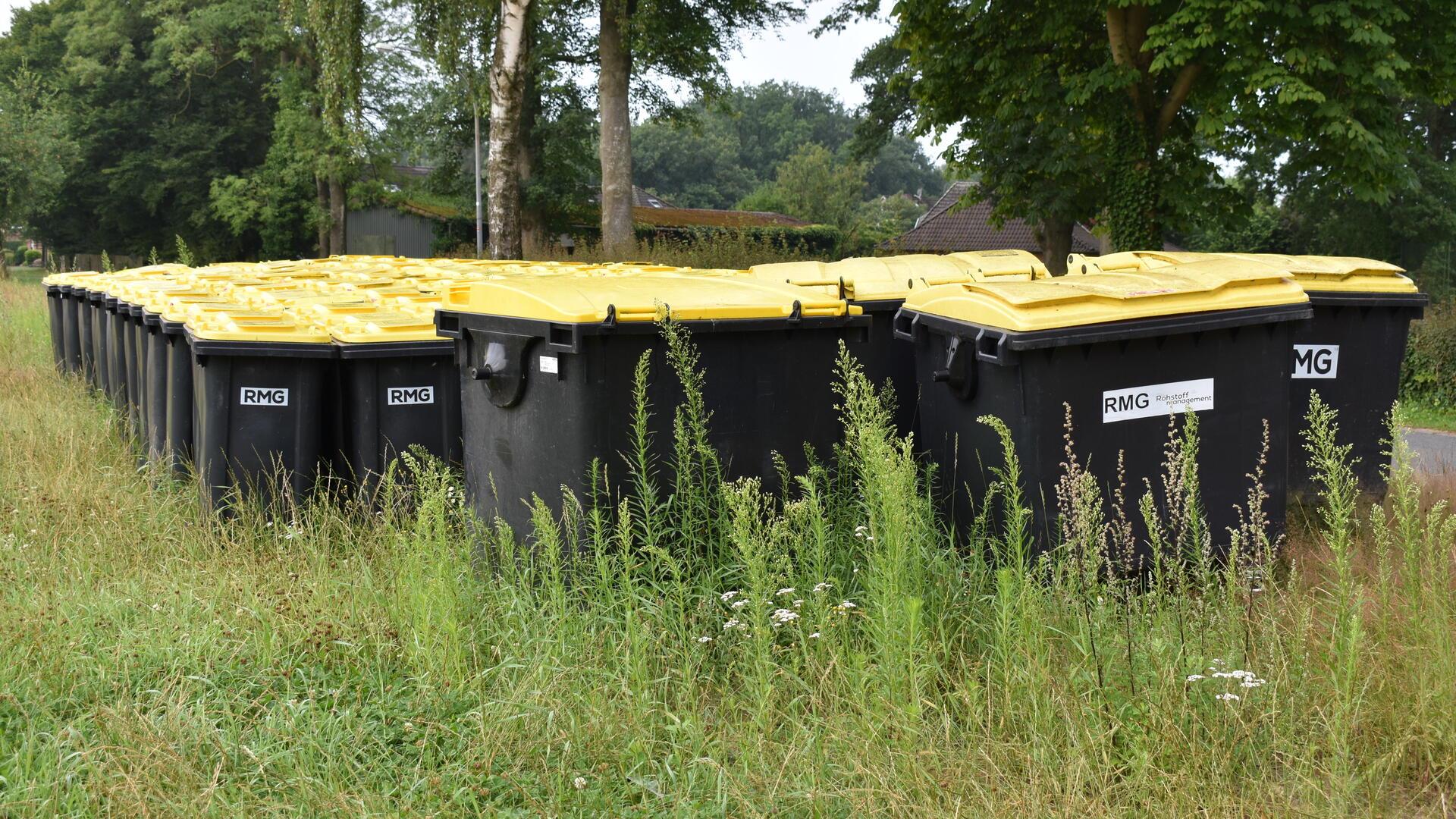 Viele Mülltonnen mit gelben Deckeln.