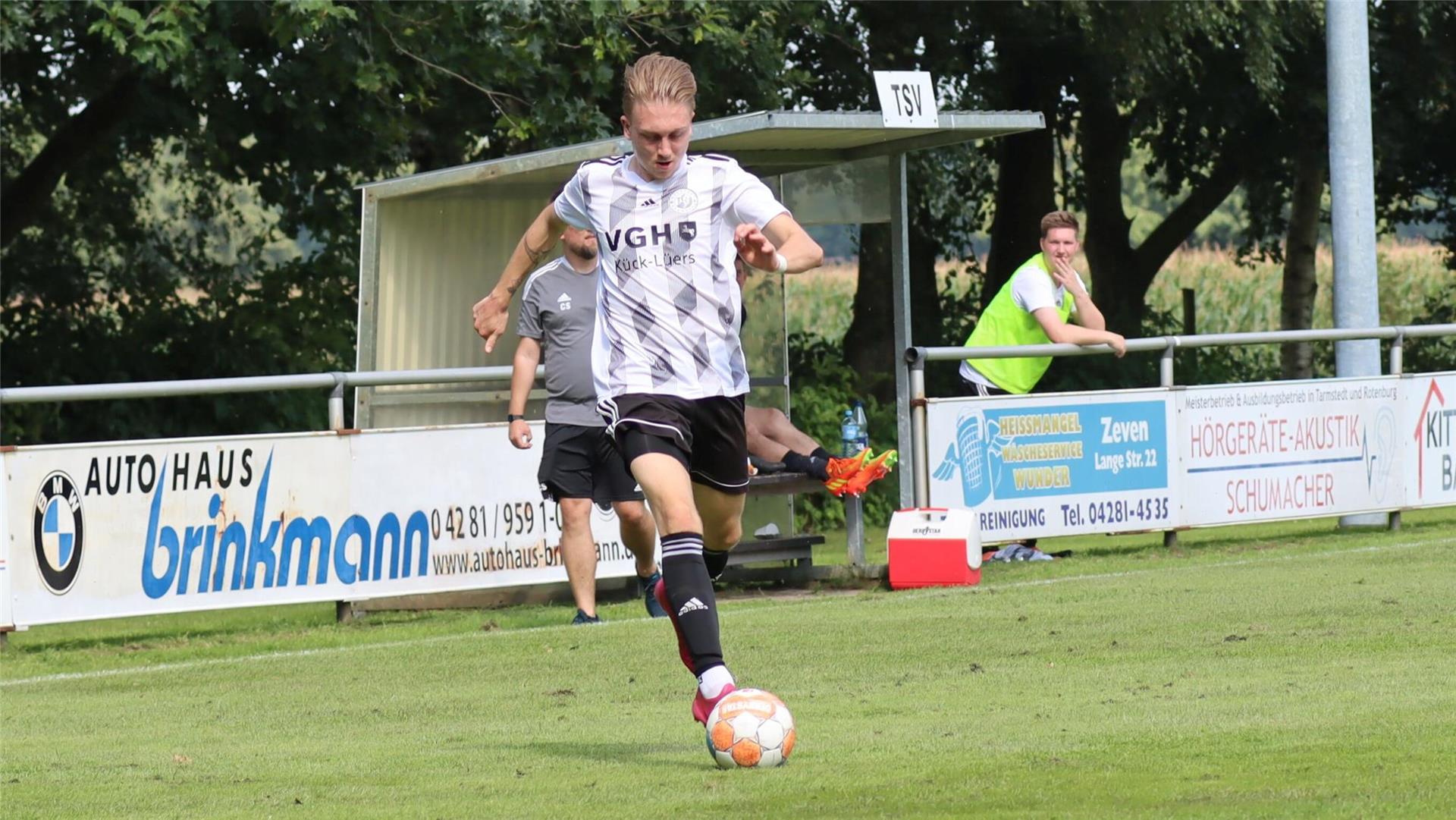 ein Mann in schwarzweißem Trikot läuft mit einem Ball