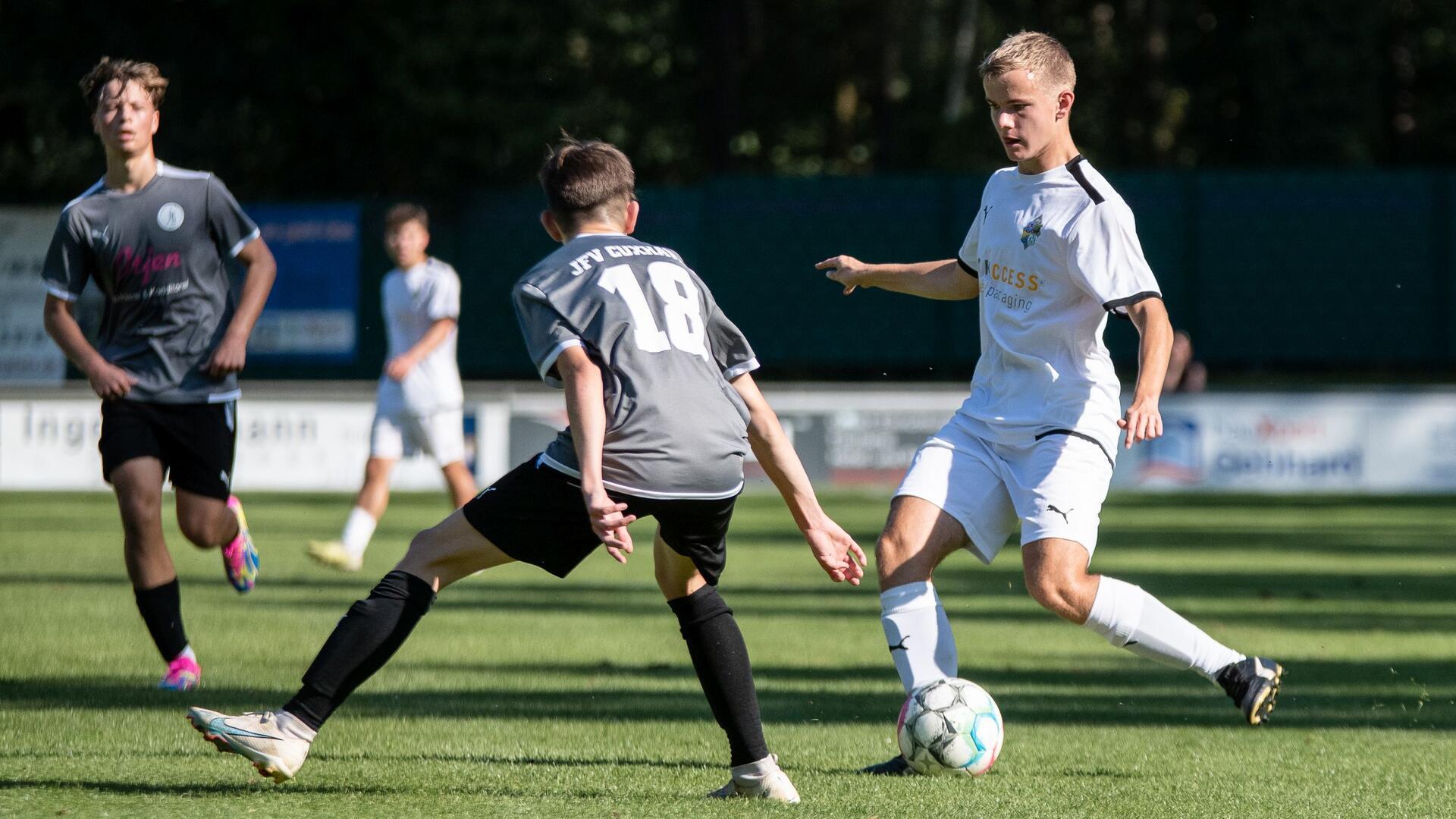 drei junge Männer spielen Fußball.