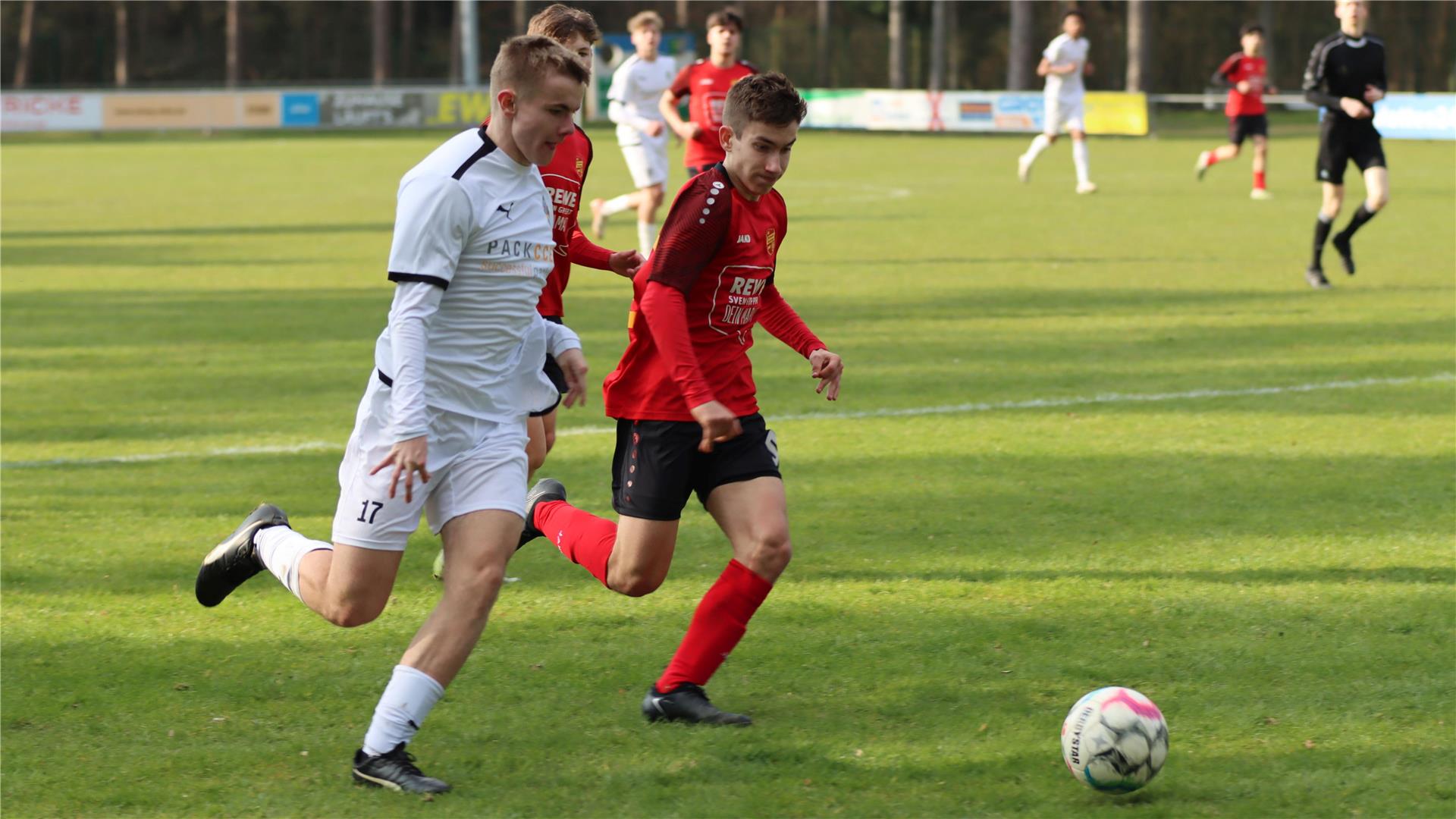 Zwei junge Männer laufen hinter einem Ball her.