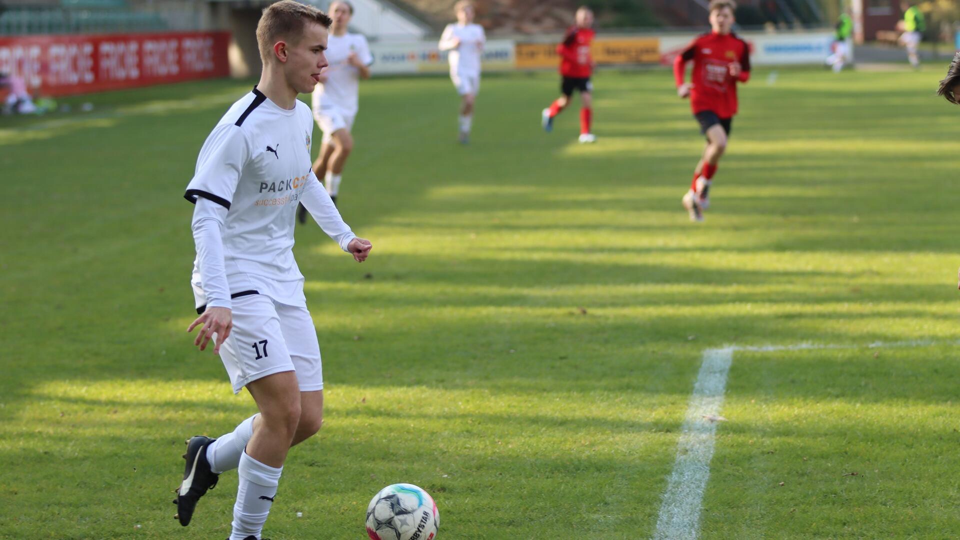 ein Jugendlicher im weißen Trikot mit einem Fußball