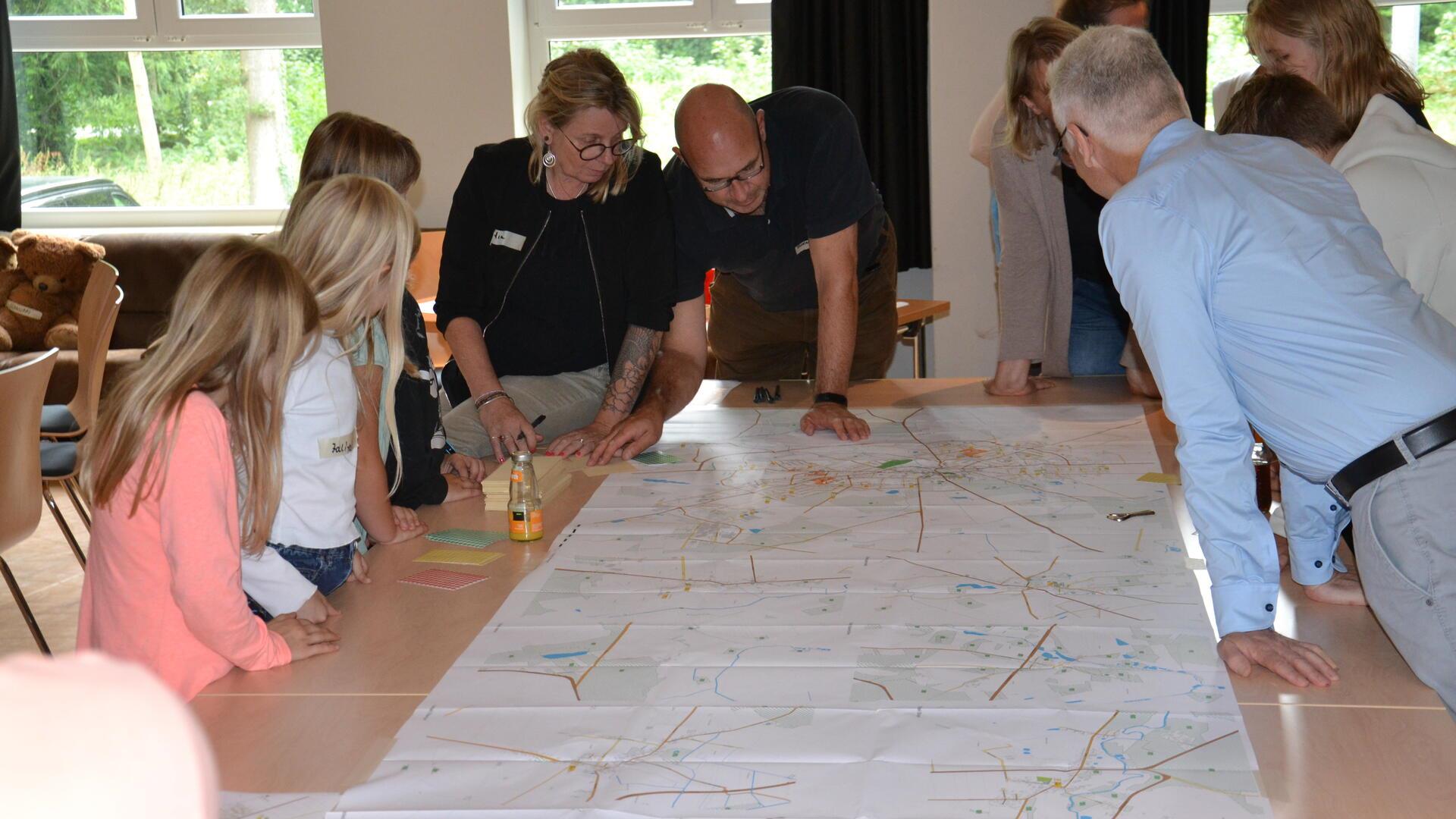 Kinder und Erwachsene beugen sich über einen Stadtplan von Zeven