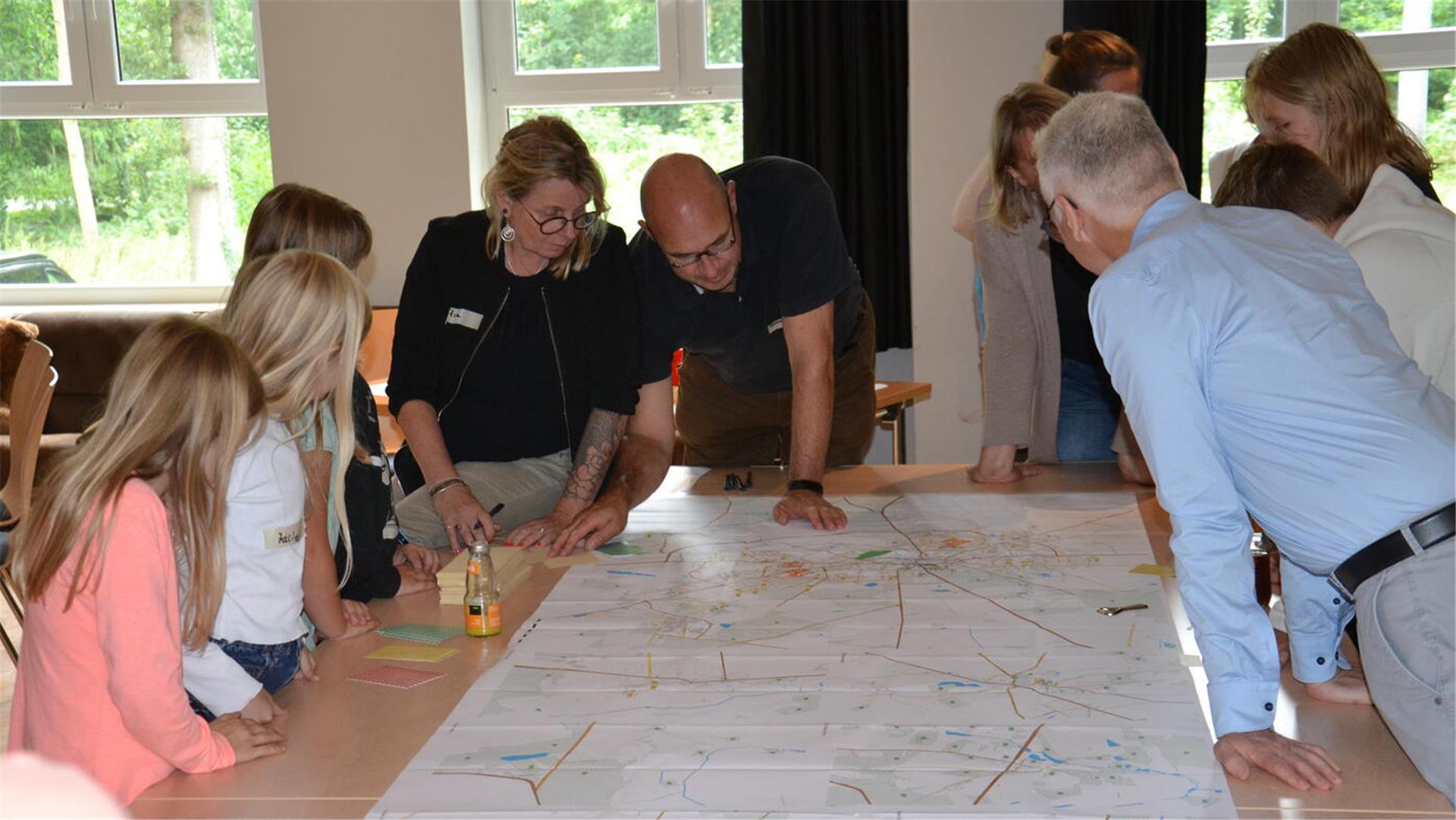 Kinder und Erwachsene beugen sich über einen Stadtplan von Zeven.