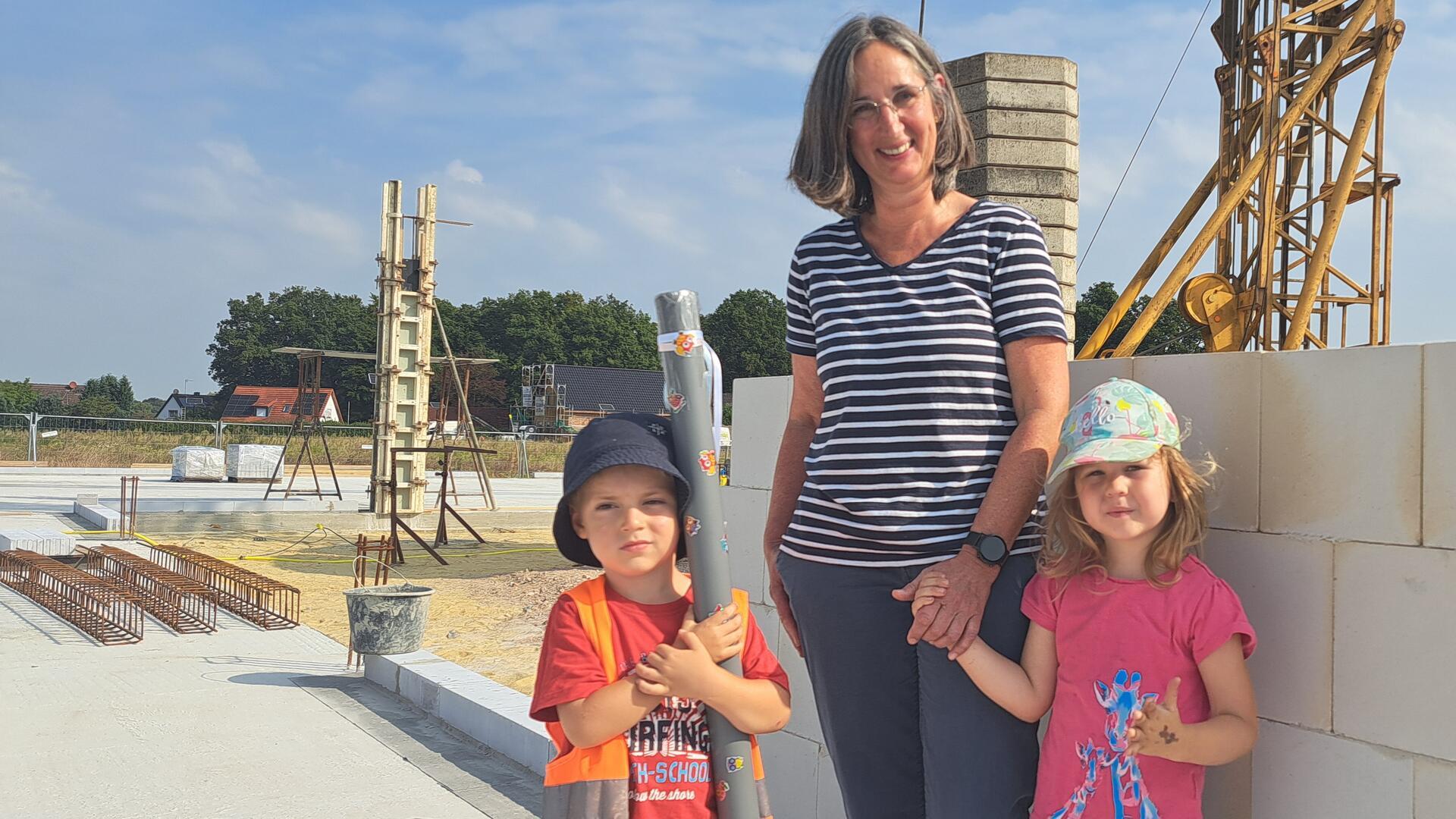 Kita-Leiterin Tanja Dietrich-Wulff ist mit Jannis und Laura bei der Grundsteinlegung in Bramstedt. Die Kinder haben eine Zeitkappsel vorbereitet. 