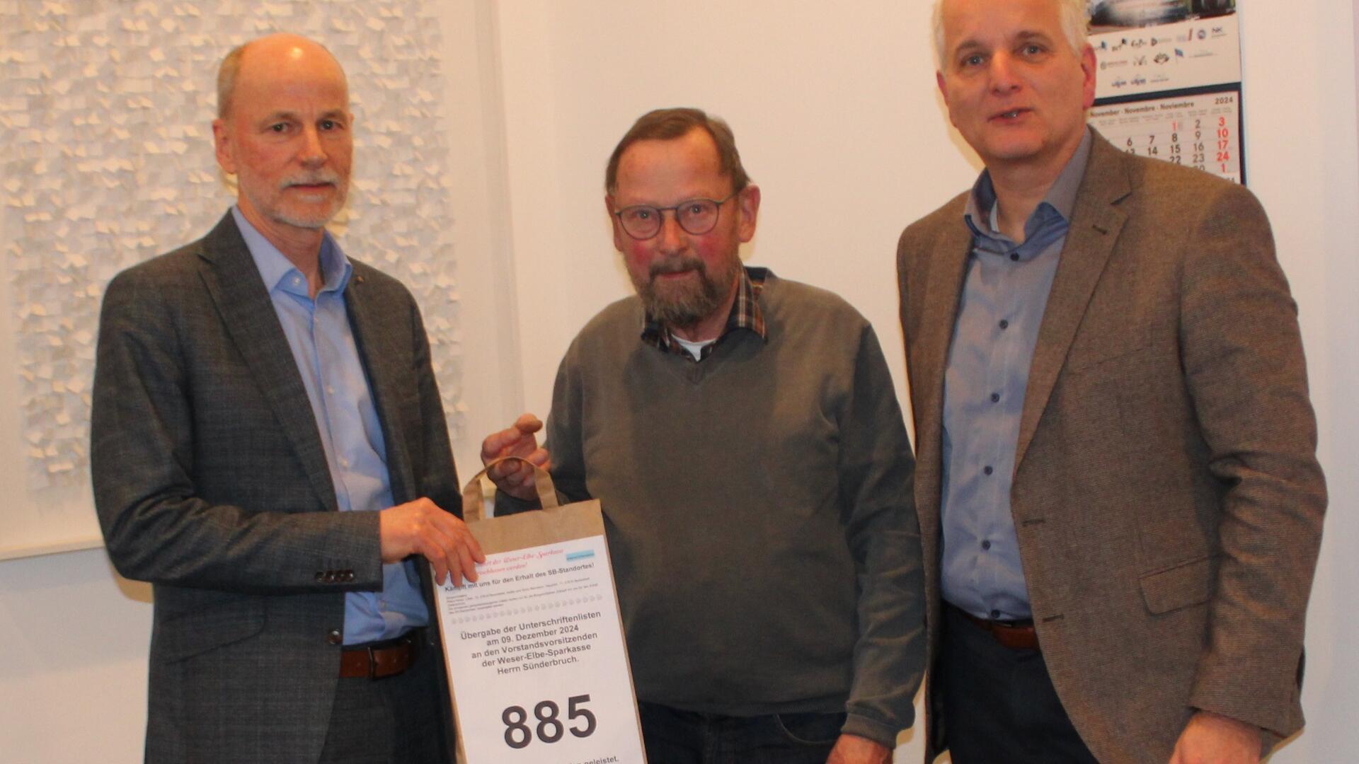 Klaus Hinze (Mitte) übergibt 885 Unterschriften für den Erhalt des Bokeler Geldautomaten an Rolf Sünderbruch (links) und Bernd Meenzen von der Wespa.