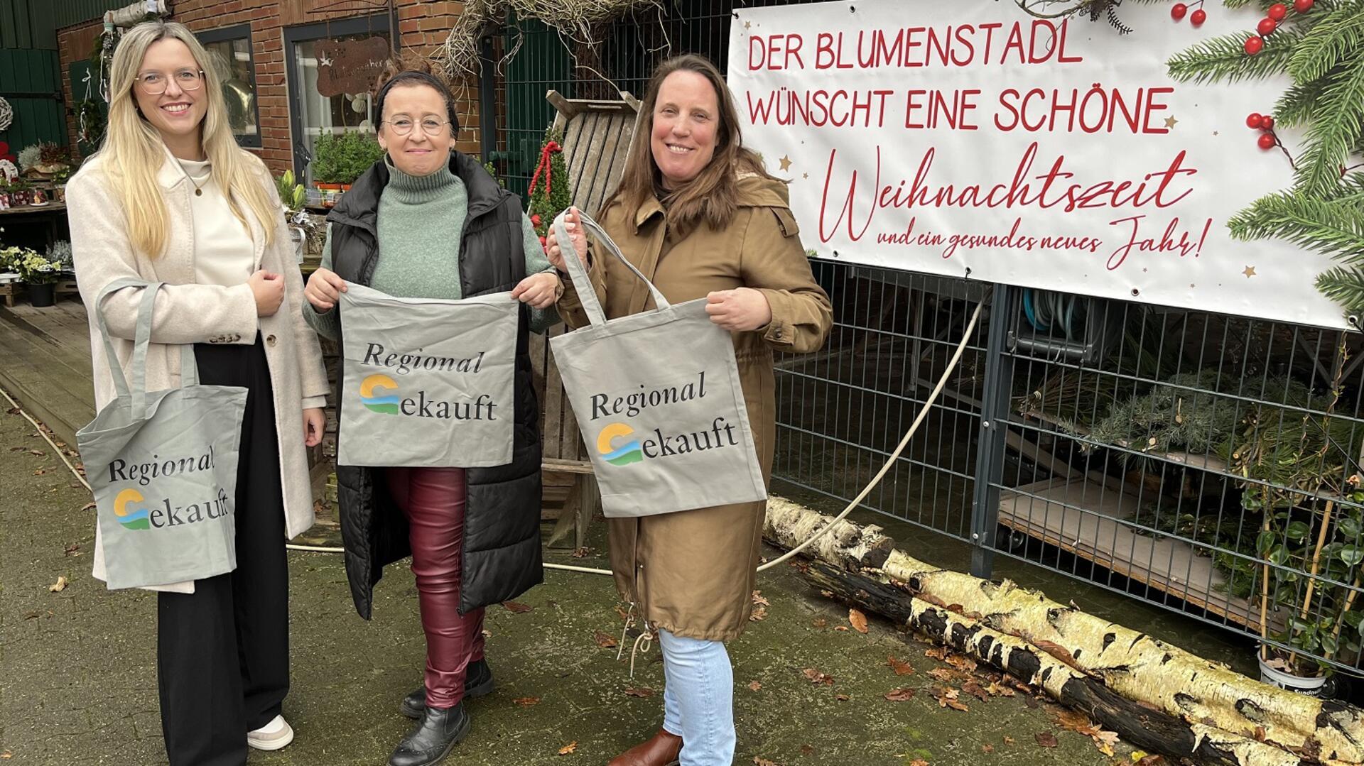 Klimaschutzmanagerin Katharina Koop (links) und Wirtschaftsförderin Katja Beier (rechts) haben die Geestland-Taschen bereits an zahlreiche Einzelhändler verteilt. Eine davon ist Bärbel Pape, die ein Blumengeschäft in Kührstedt führt.