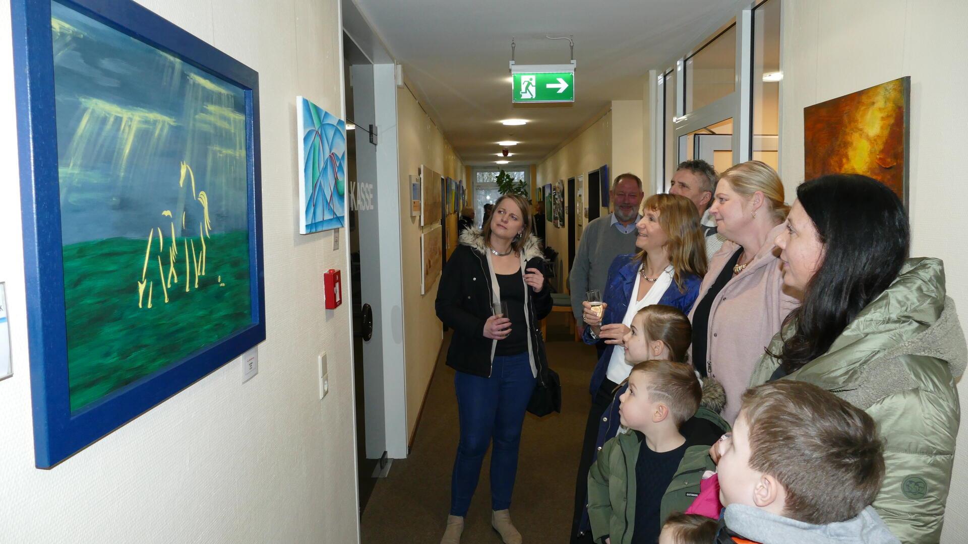 Künstlerin Christina Götte (mit Sektglas) zeigt ihren Gästen bei der Vernissage ihre Bilder. 