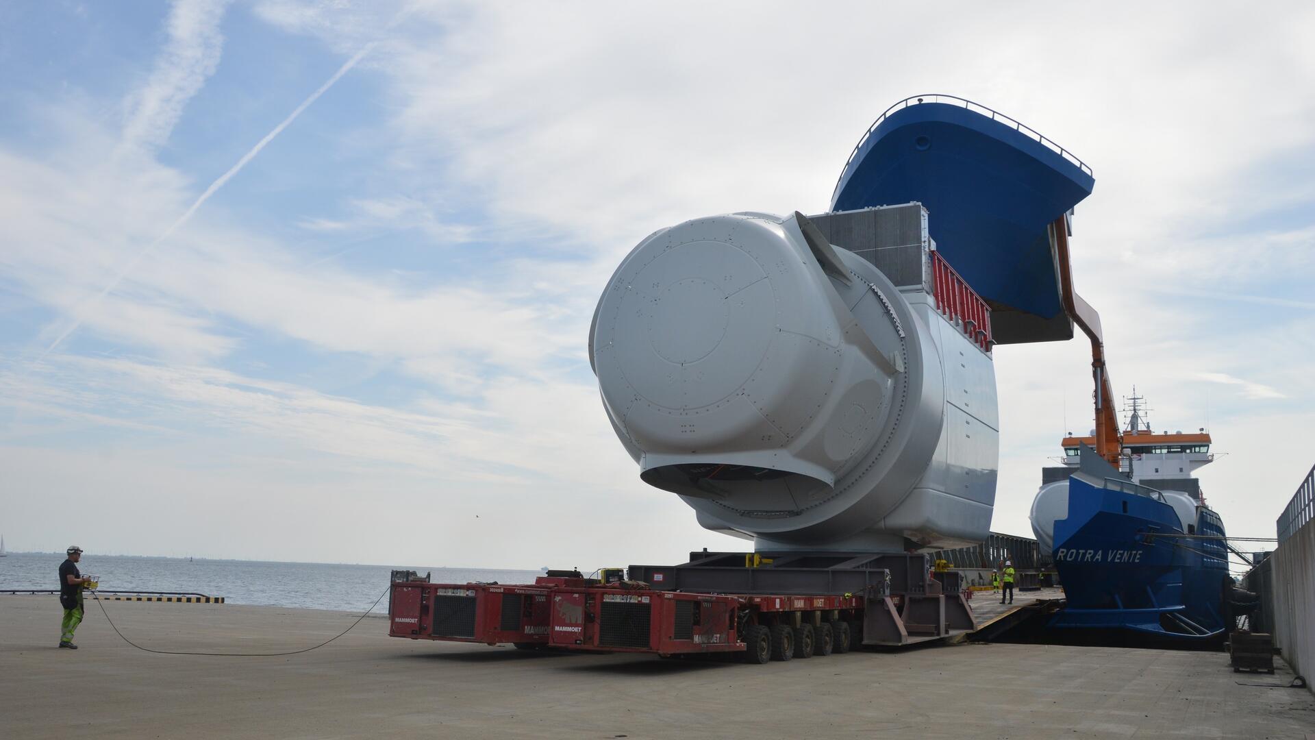 Langsame Fahrt voraus: Ein Maschinenhaus für eine Offshore-Windkraftanlage von Siemens Gamesa bei der Verladung auf die „Rotra Vente“ in Cuxhaven. Sie wird auf zwei Modulfahrzeugen auf das Schiff gefahren, das dafür den Bug hochgeklappt hat. Links ist Fahrer Jakob Lauridsen zu sehen.