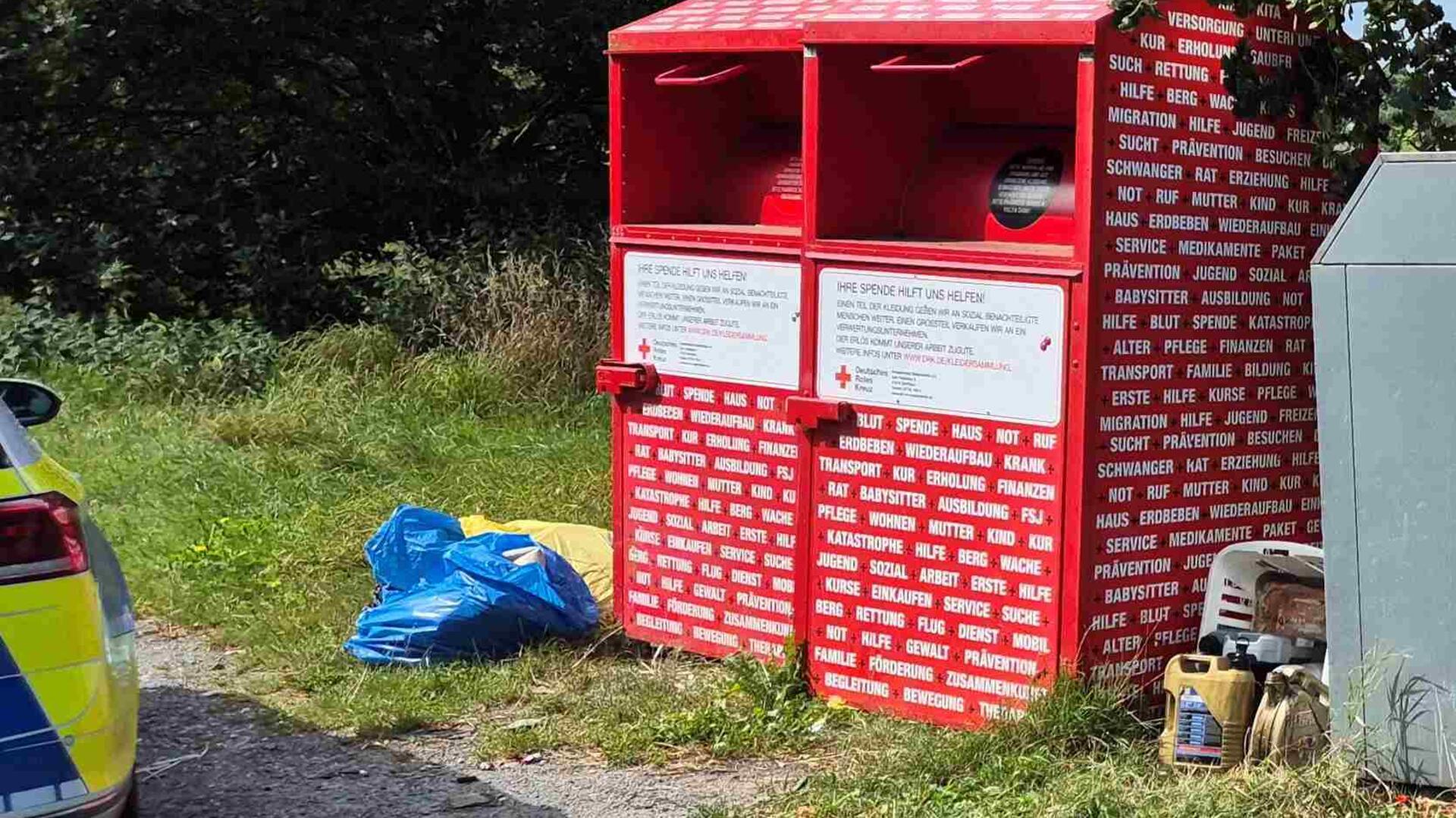 Zwischen und neben Altkleider- und Glascontainern liegen einige Altölkanister auf dem Boden.