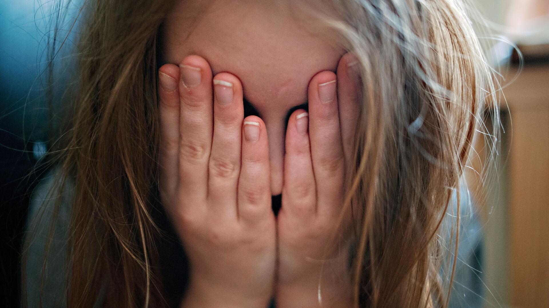 Mädchen mit Händen vor dem Gesicht