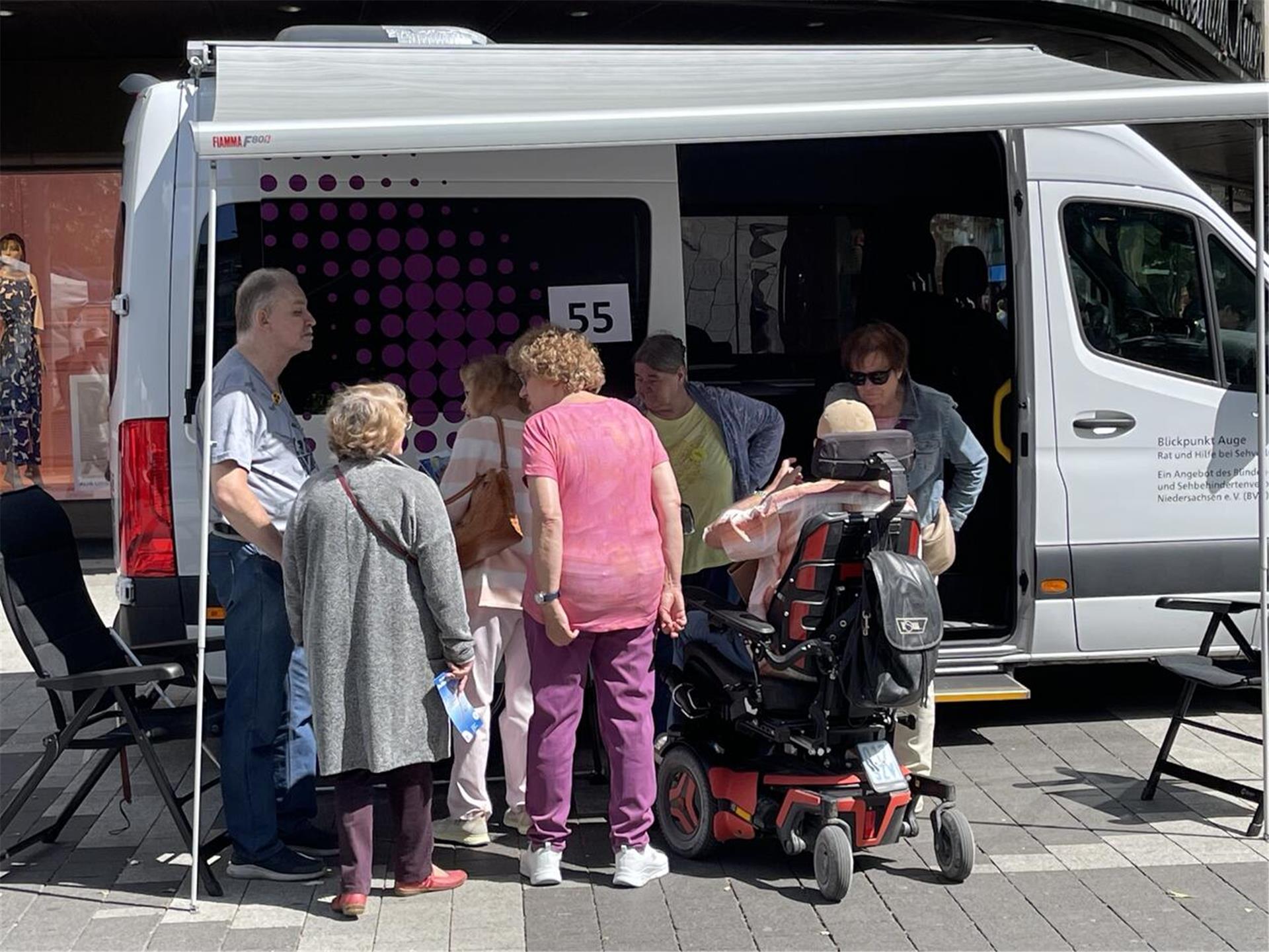 Frauen und Männer stehen vor einem Kleinbus.