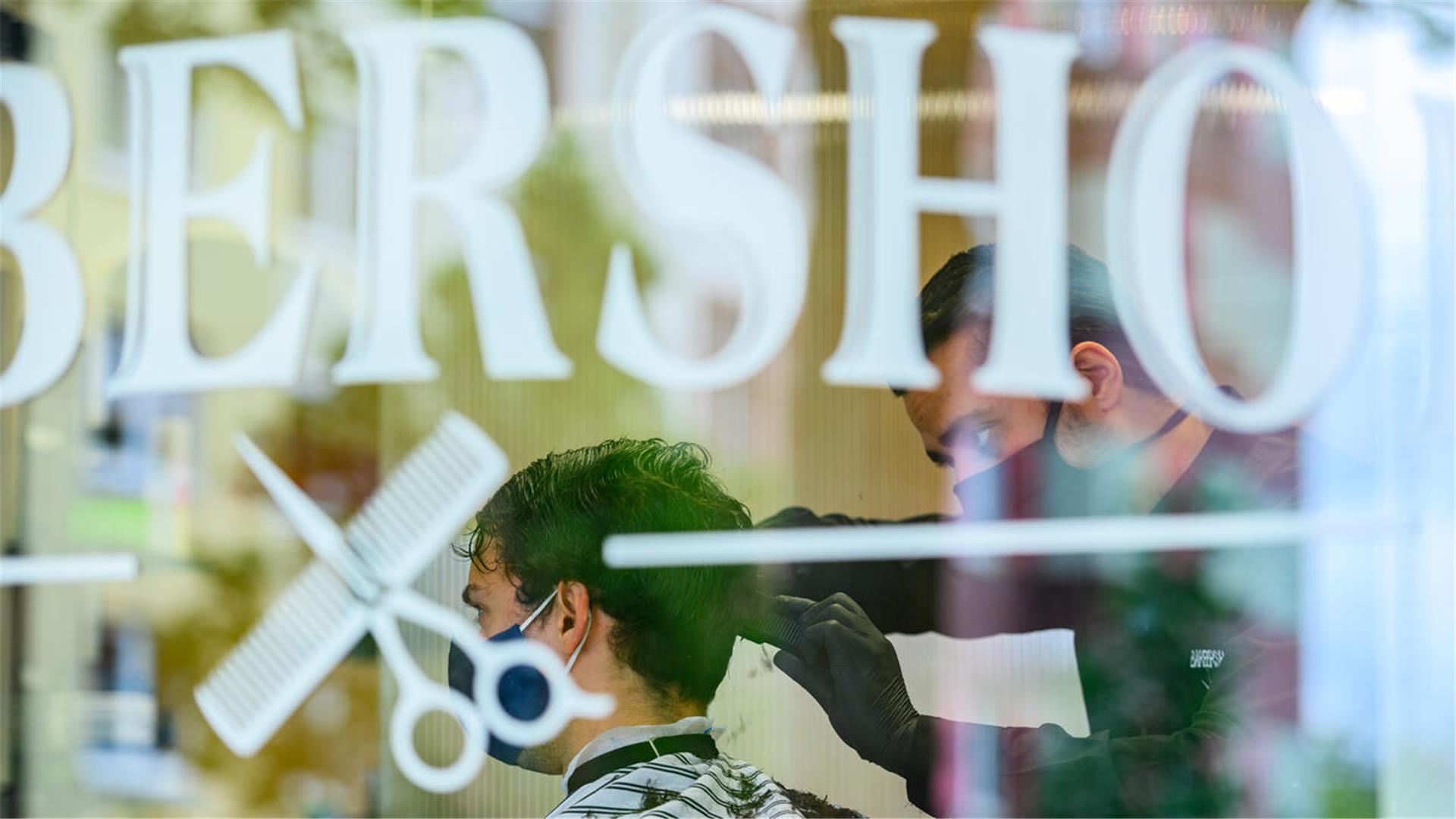 Ein Friseur schneidet einem Kunden im „Barbershop“ die Haare.