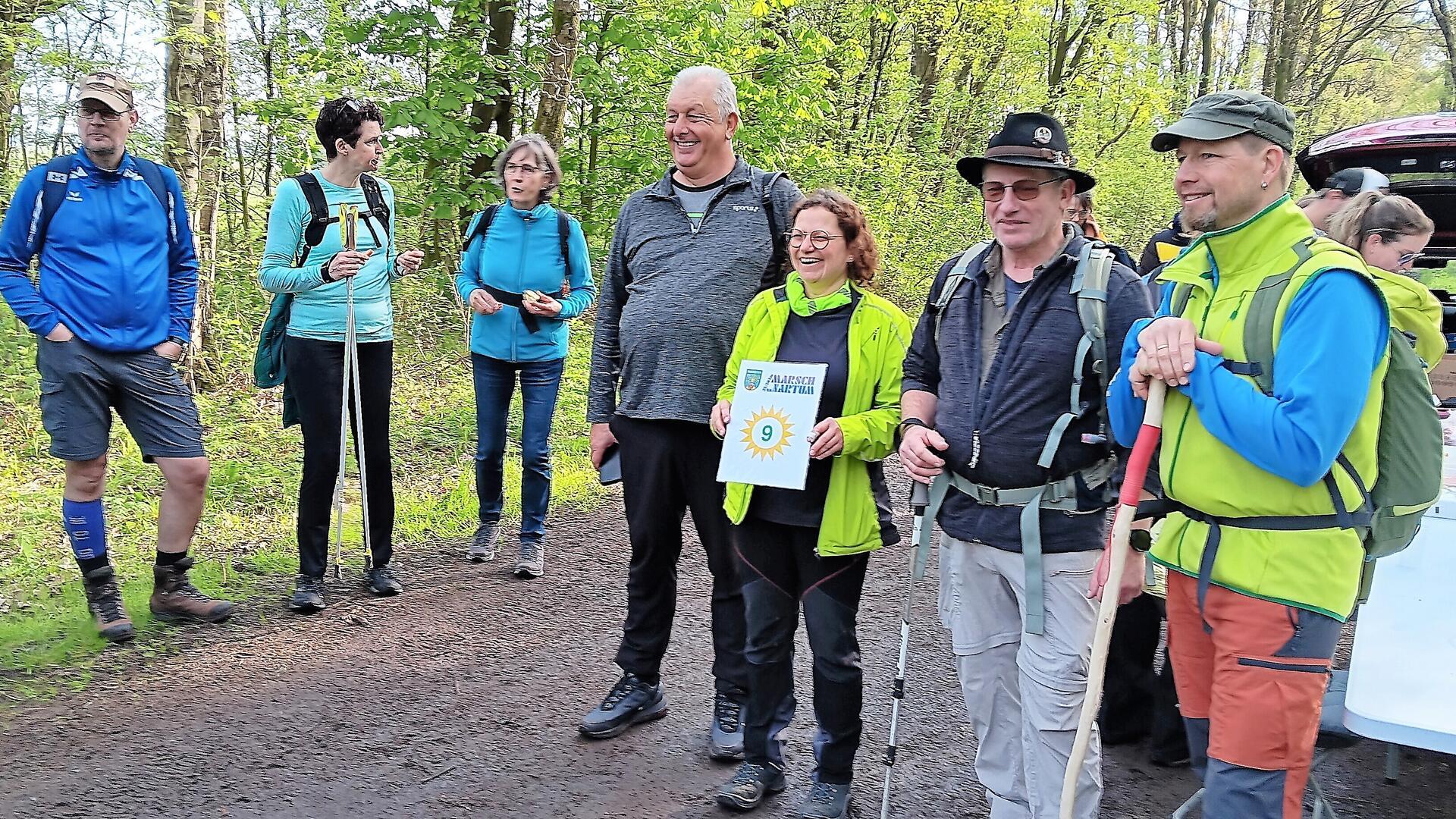 Nach den ersten 9 Kilometern gab es Getränke, Snacks und den ersten Stempel in den Wanderpass. Birgit Eckhoff vom Organisationsteam inmitten wanderfreudiger Teilnehmer,