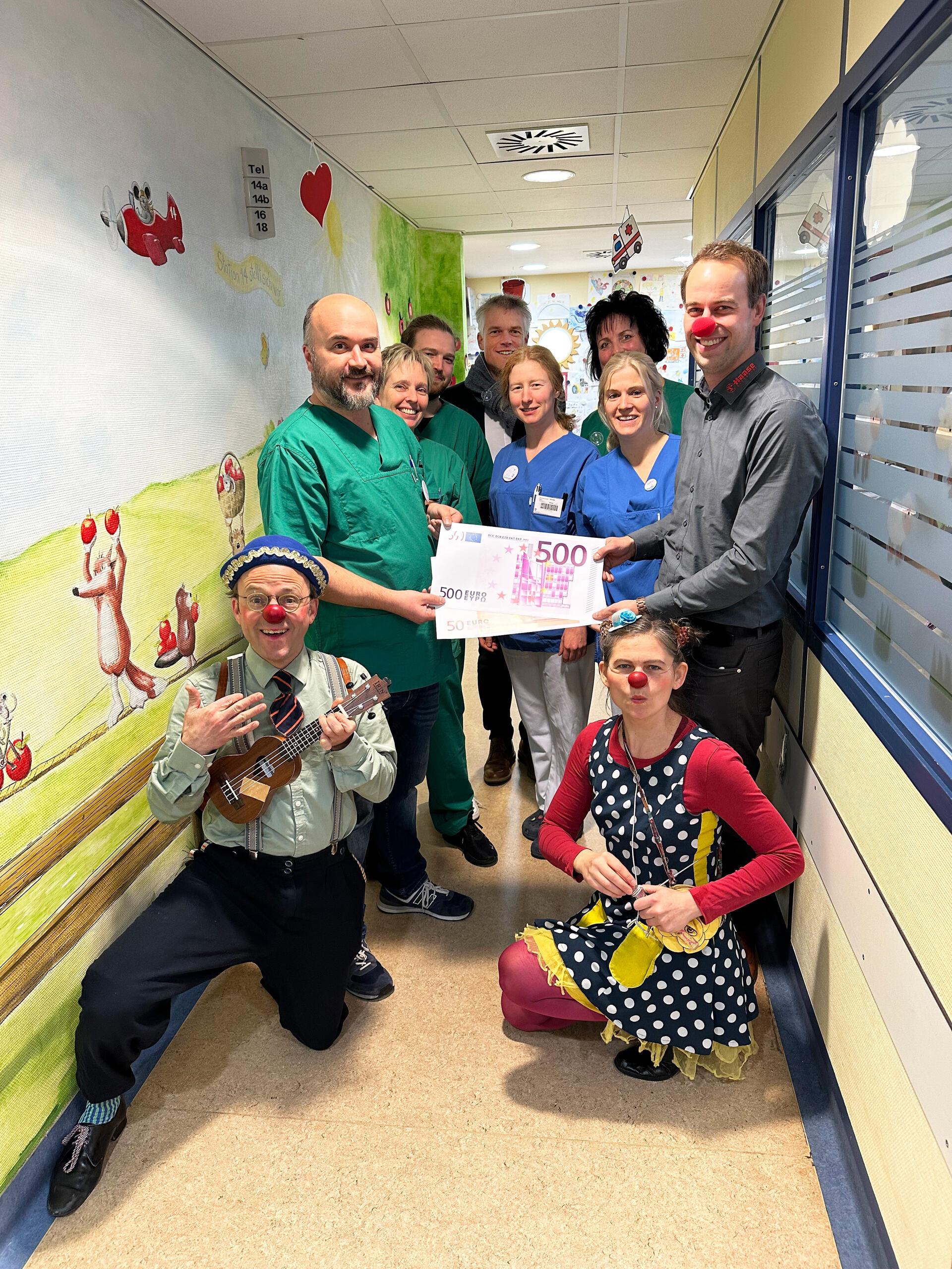 Nils Schlesselmann (rechts) vom Unternehmen Holz Haase Baustoffe überreicht eine Spende an das Team der Kinderklinik