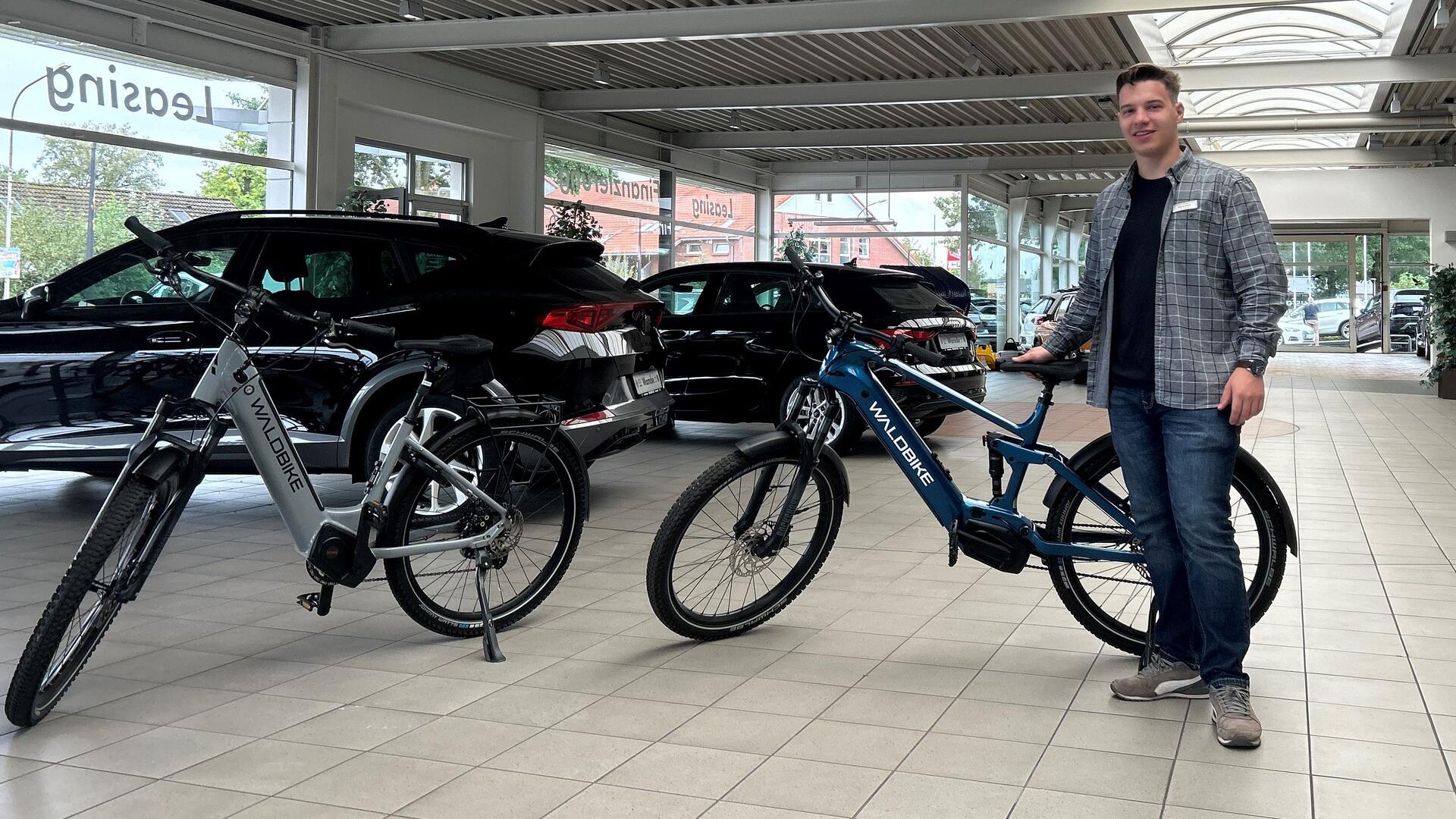 Ein junger Mann steht neben zwei E-Bikes und blickt in die Kamera.